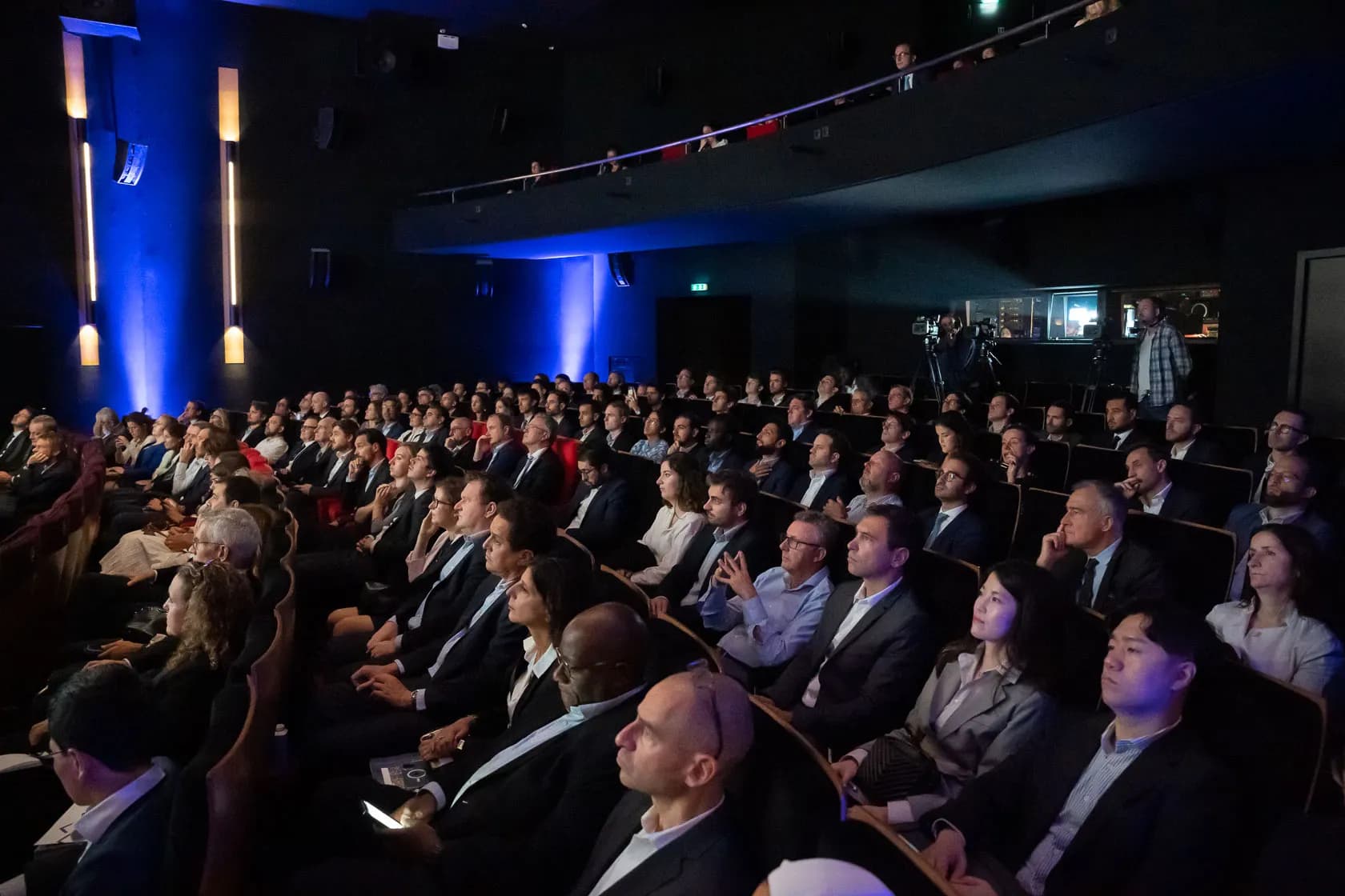 Public en conférence, salle comble sous un éclairage bleu