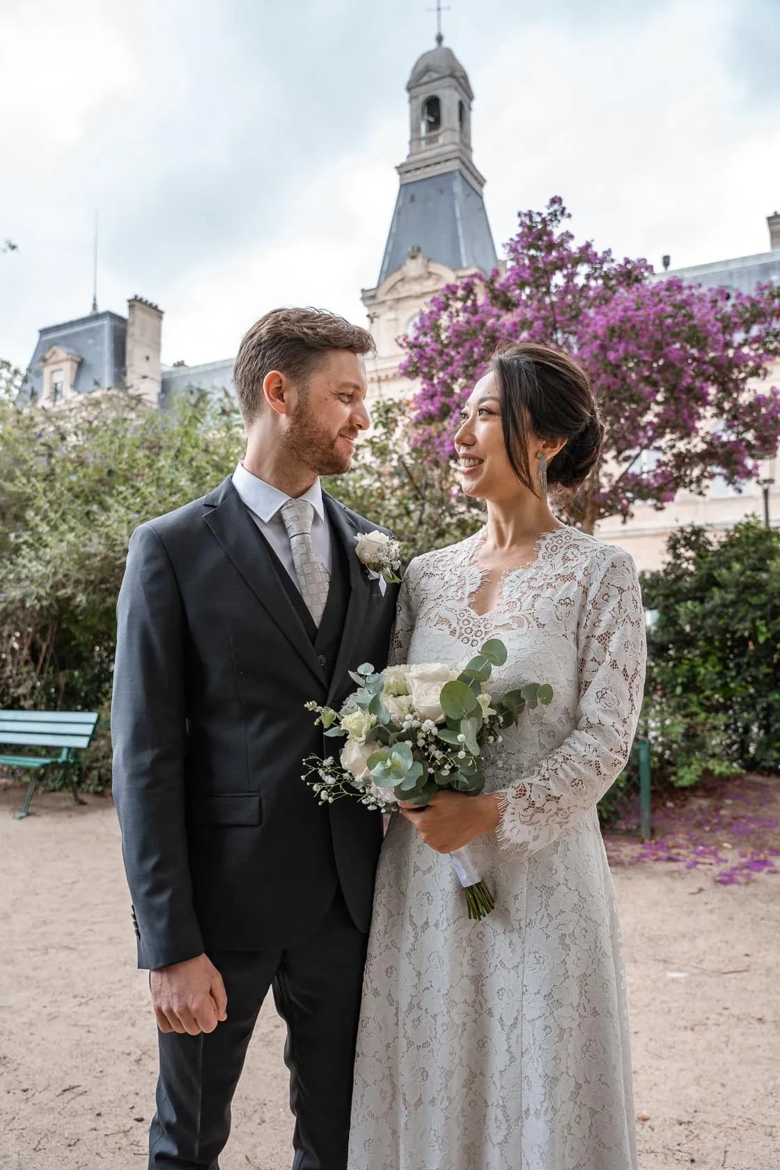 Les mariés se regardant tendrement devant un arbre aux fleurs roses