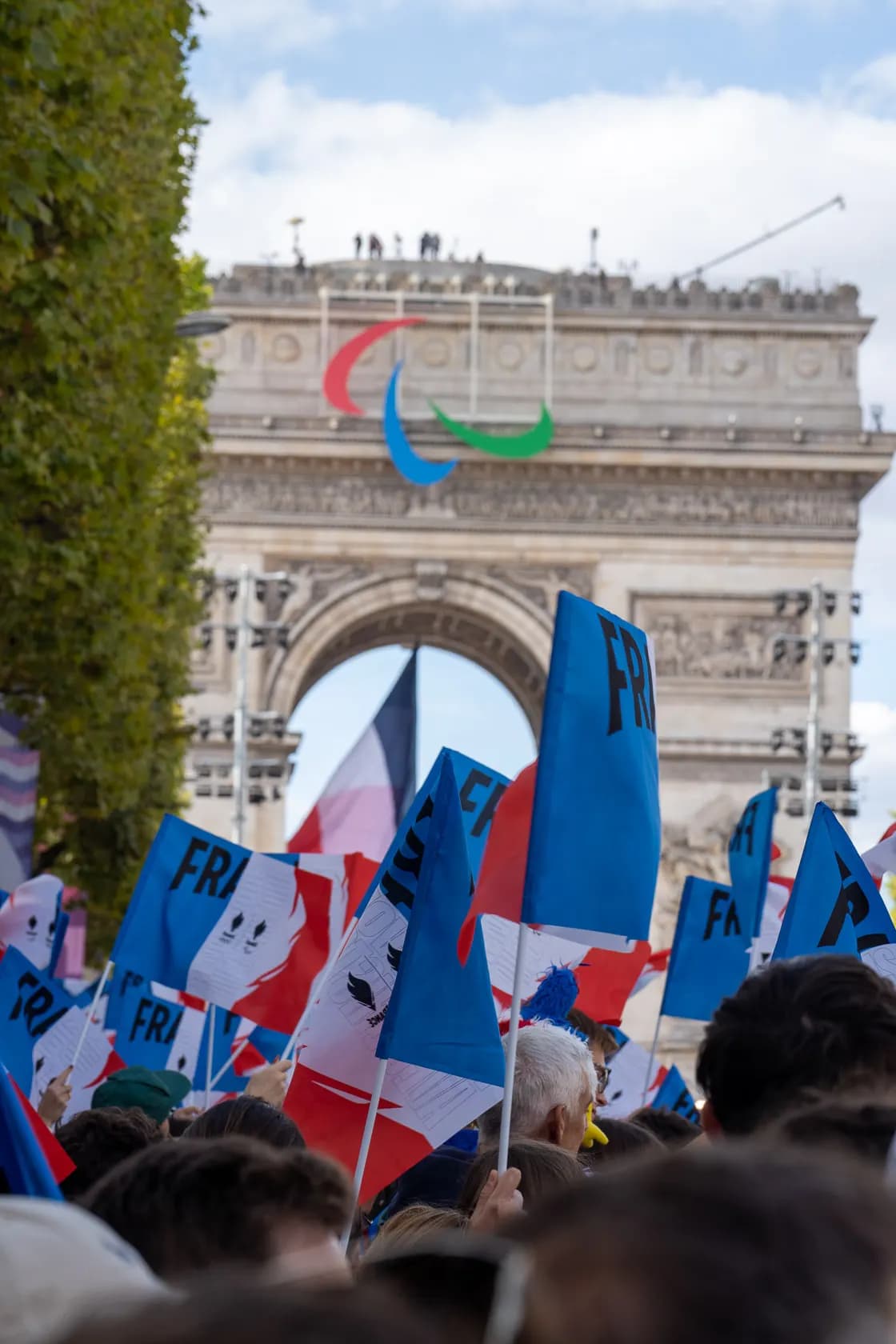 Foule rassemblée, drapeaux devant l'Arc de Triomphe