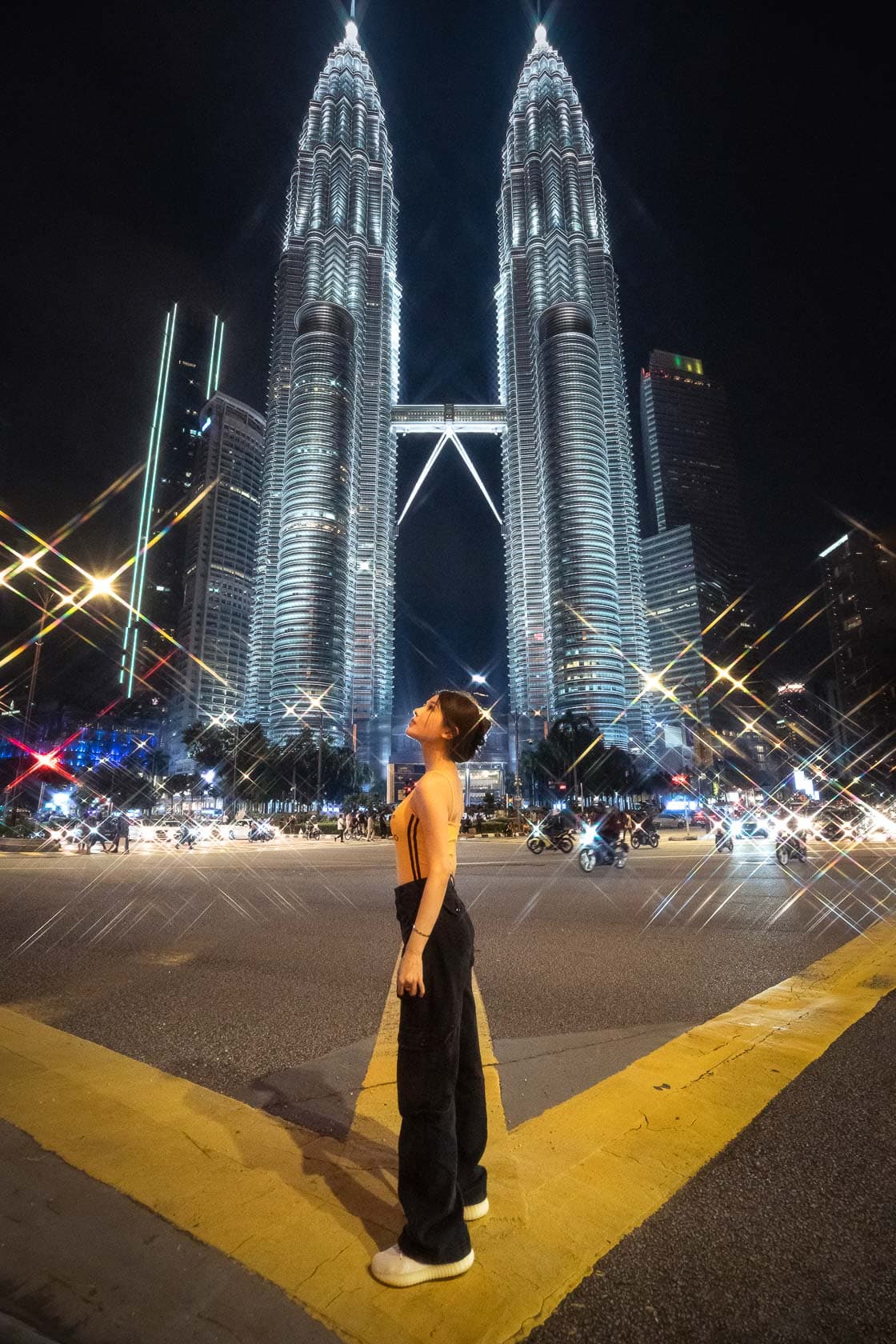 Jeune femme regardant les tours Petronas illuminées la nuit à Kuala Lumpur