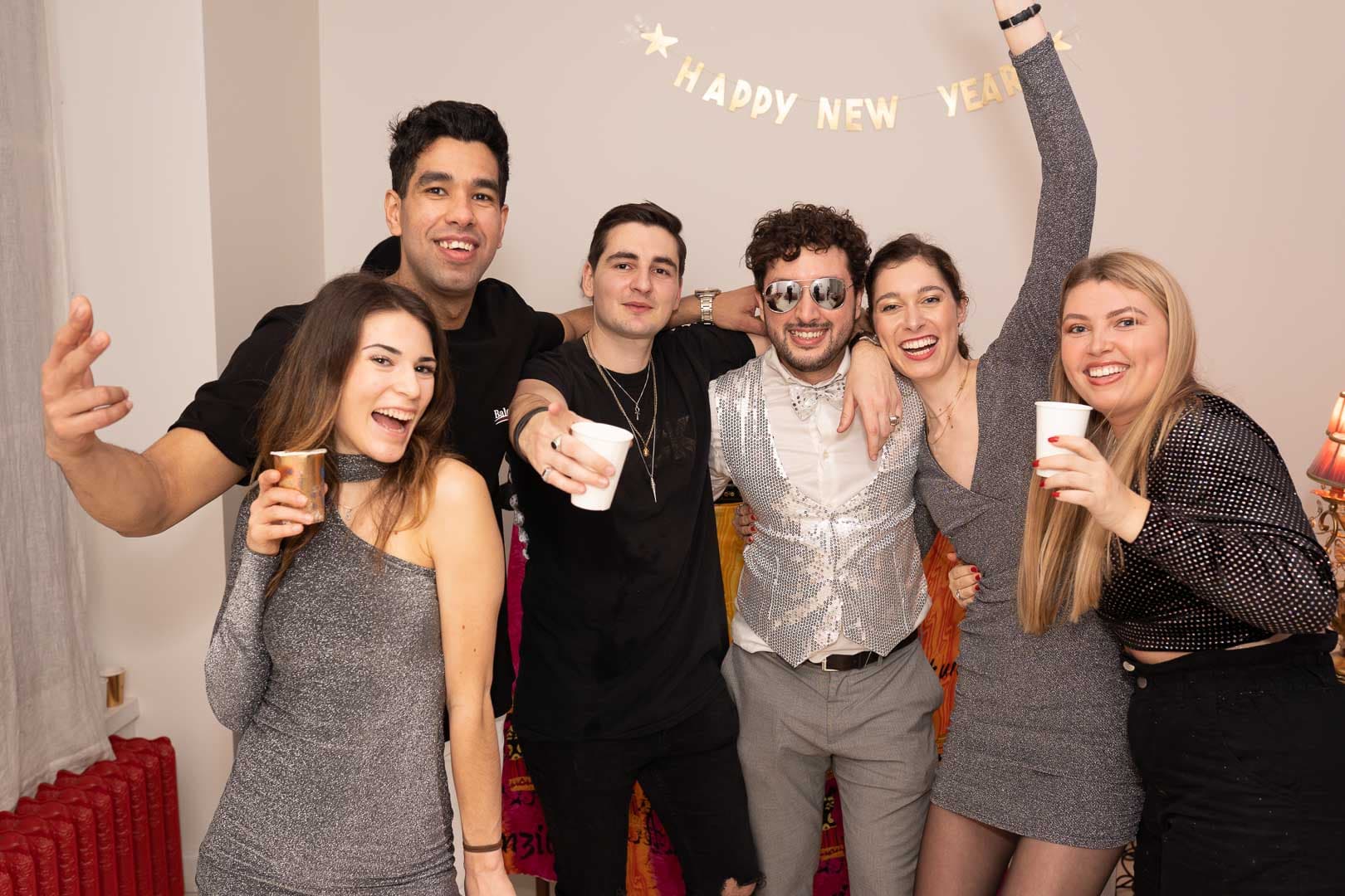 Photo de groupe conviviale de la soirée du Nouvel An, montrant des invités souriants