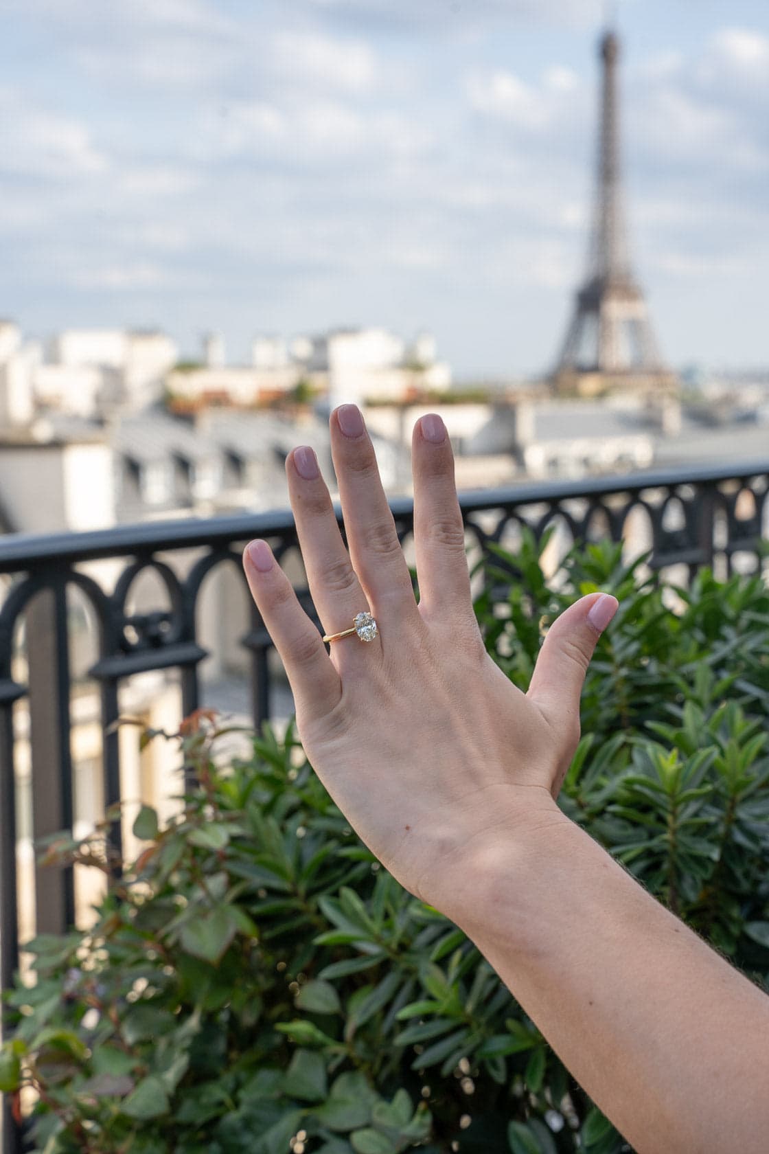 Main portant une bague de fiançailles avec en arrière-plan la Tour Eiffel et les toits de Paris