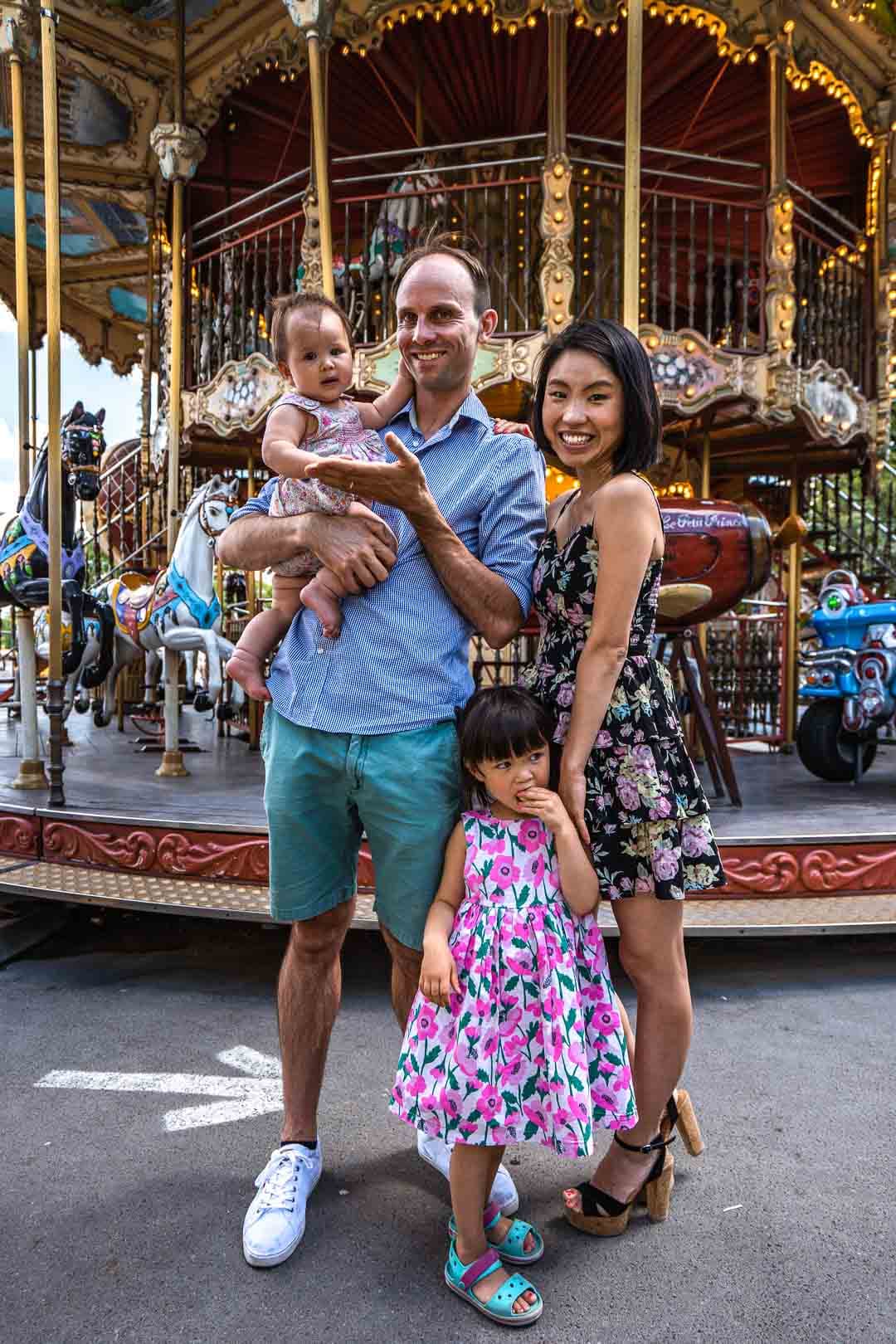 Famille de quatre personnes souriant devant un carrousel illuminé à Paris