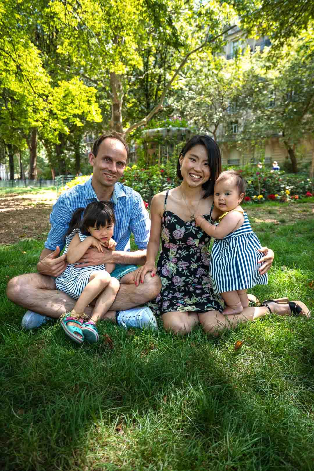 Famille de quatre personnes assise sur l'herbe dans un parc ensoleillé à Paris