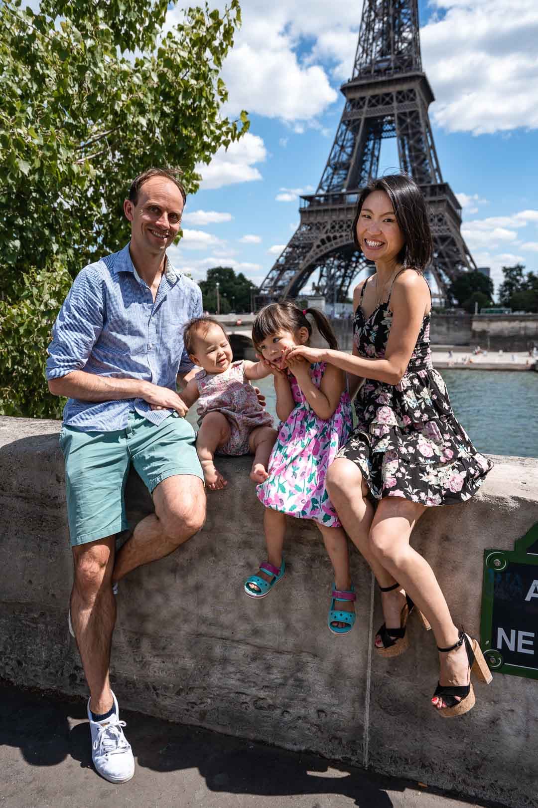 Famille de quatre personnes souriant avec la Tour Eiffel en arrière-plan à Paris