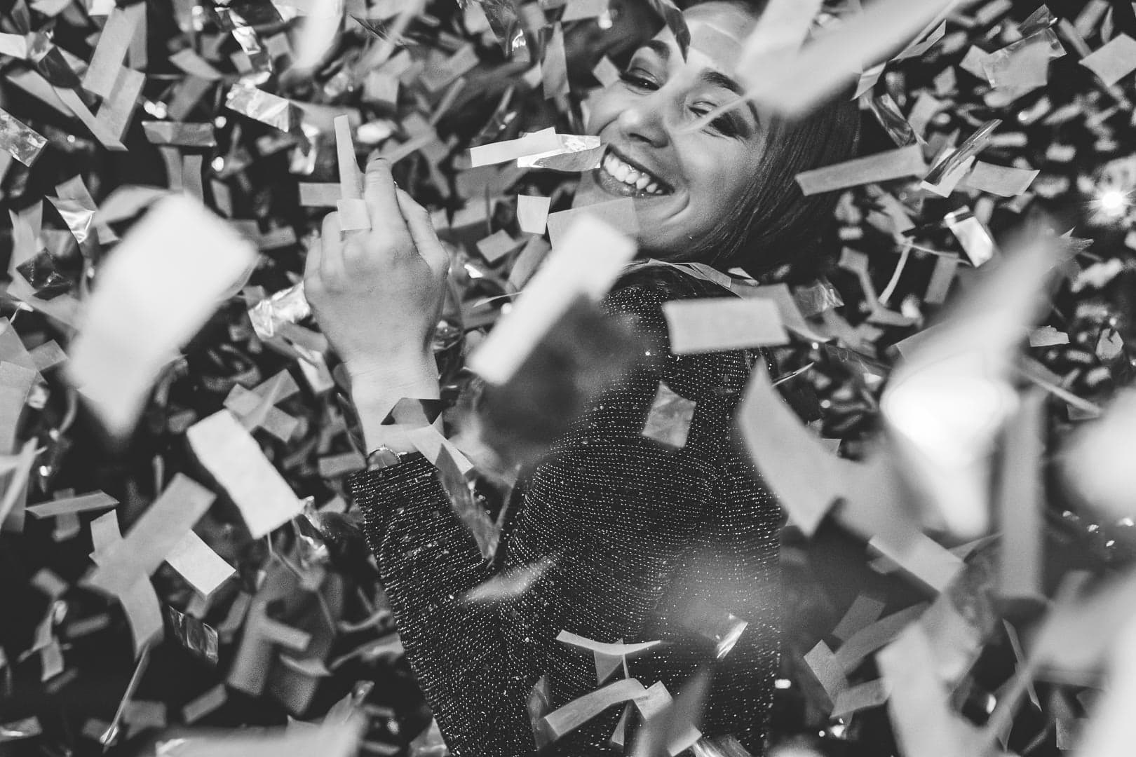 Femme dansant sous une pluie de cotillons en noir et blanc