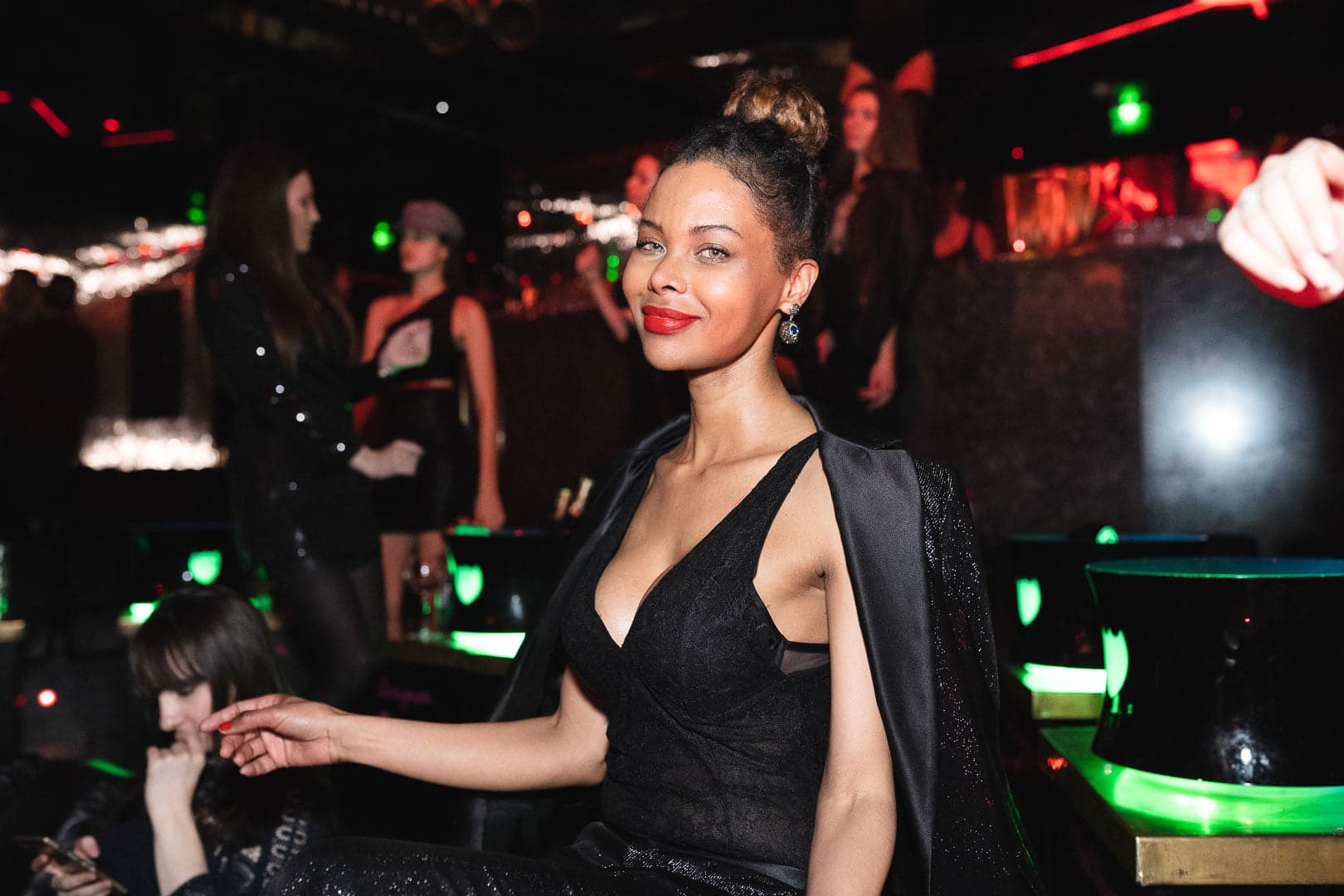 Portrait d'une femme assise à une table dans la VIP Room, incarnant l'élégance