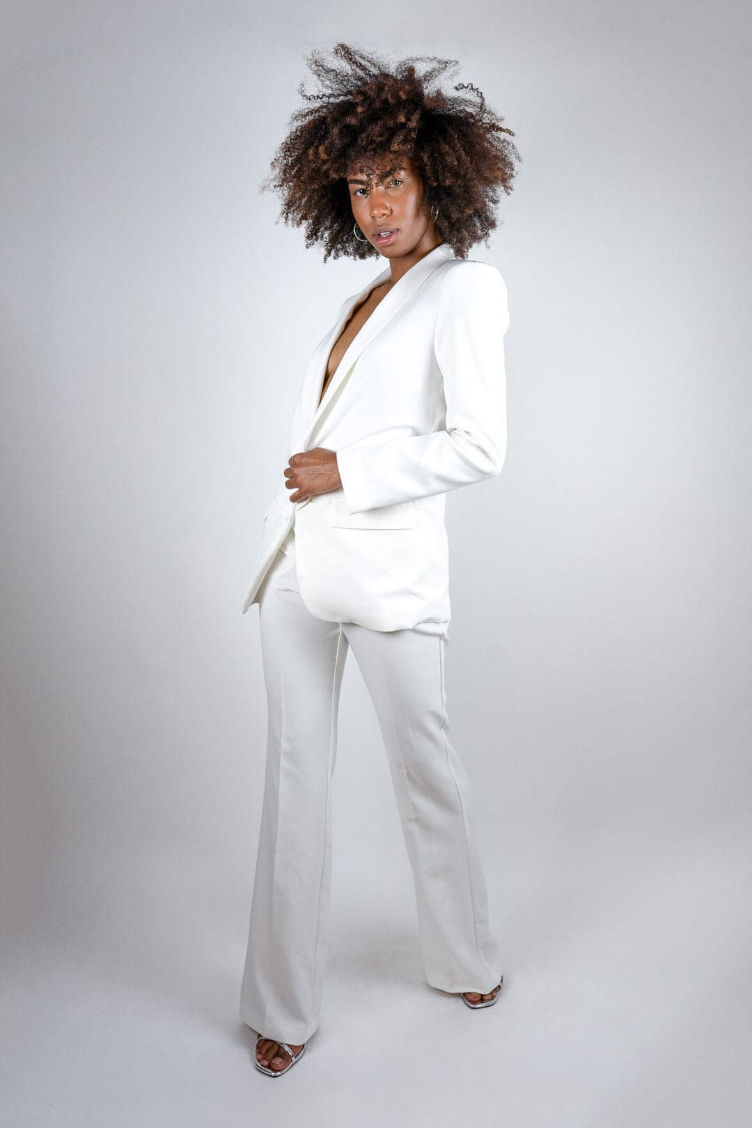 Femme en tailleur blanc, cheveux afro, en studio