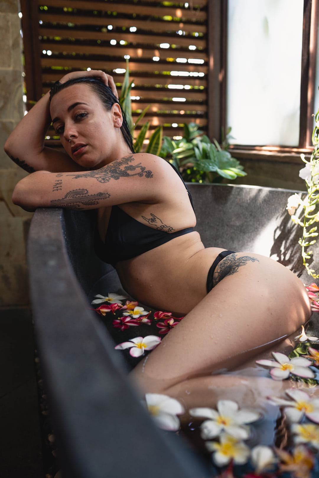 Photographie professionnelle de femme tatouée en maillot de bain dans une baignoire avec fleurs