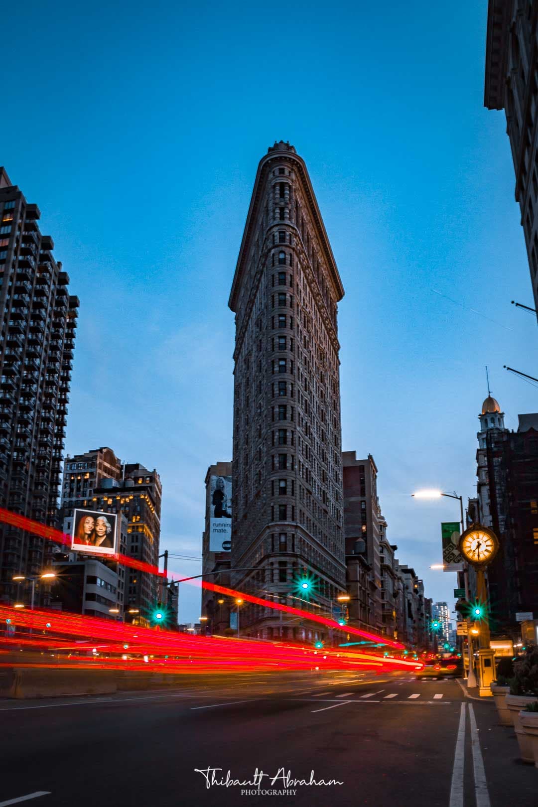 Un trait de lumière passe devant le Flat Iron Building à Manhattan pendant l'heure bleue