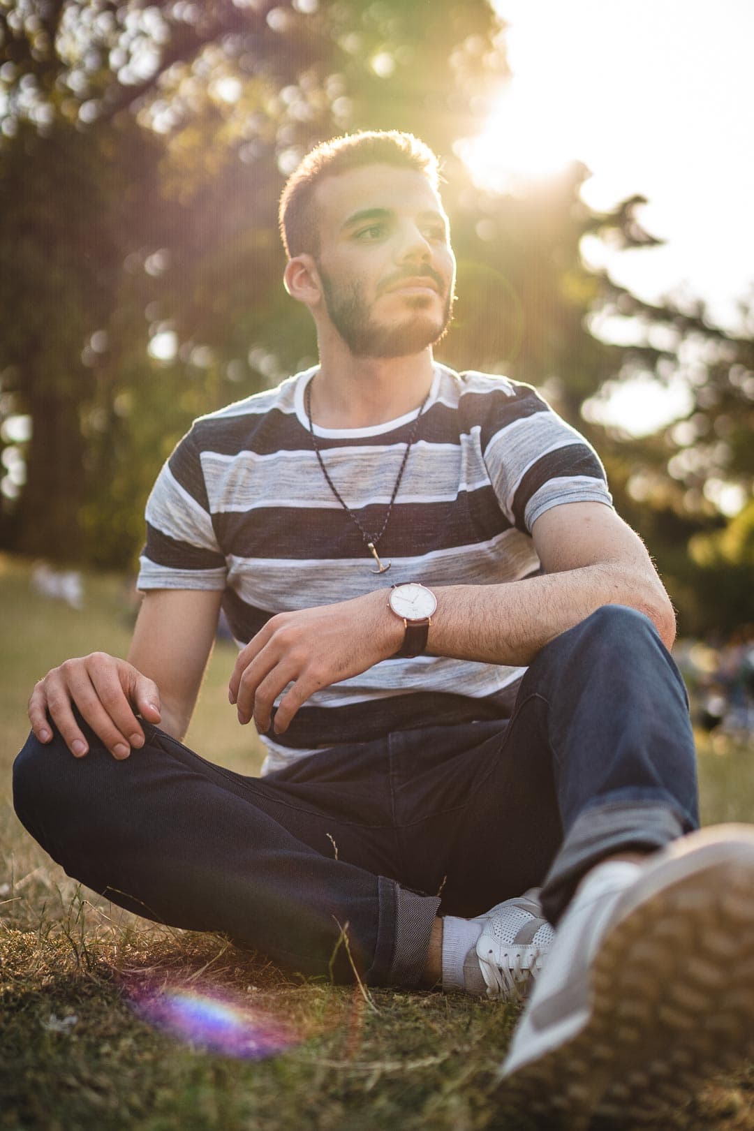 Portrait d'un homme dans un parc, il est éclairé par un rayon de soleil