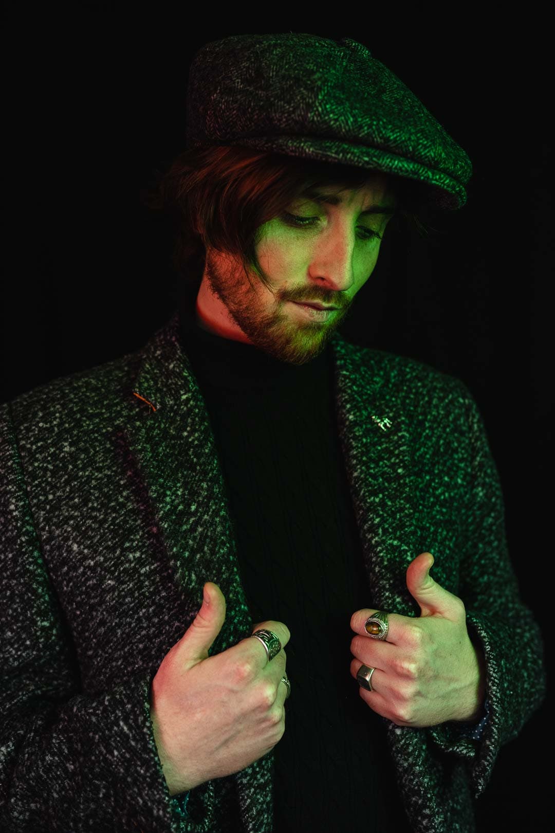 Portrait d'un homme habillé d'une veste en tweed sur un fond noir avec des reflets de lumière verts