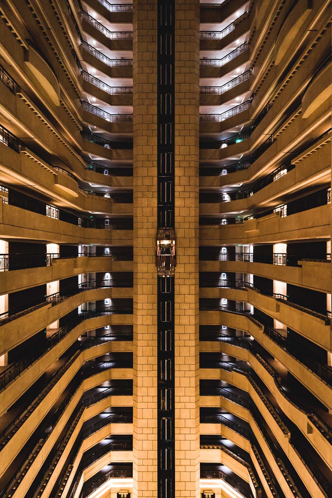Vue verticale symétrique dans l'atrium d'un hôtel à Shanghai, coursives circulaires superposées et ascenseur vitré au centre