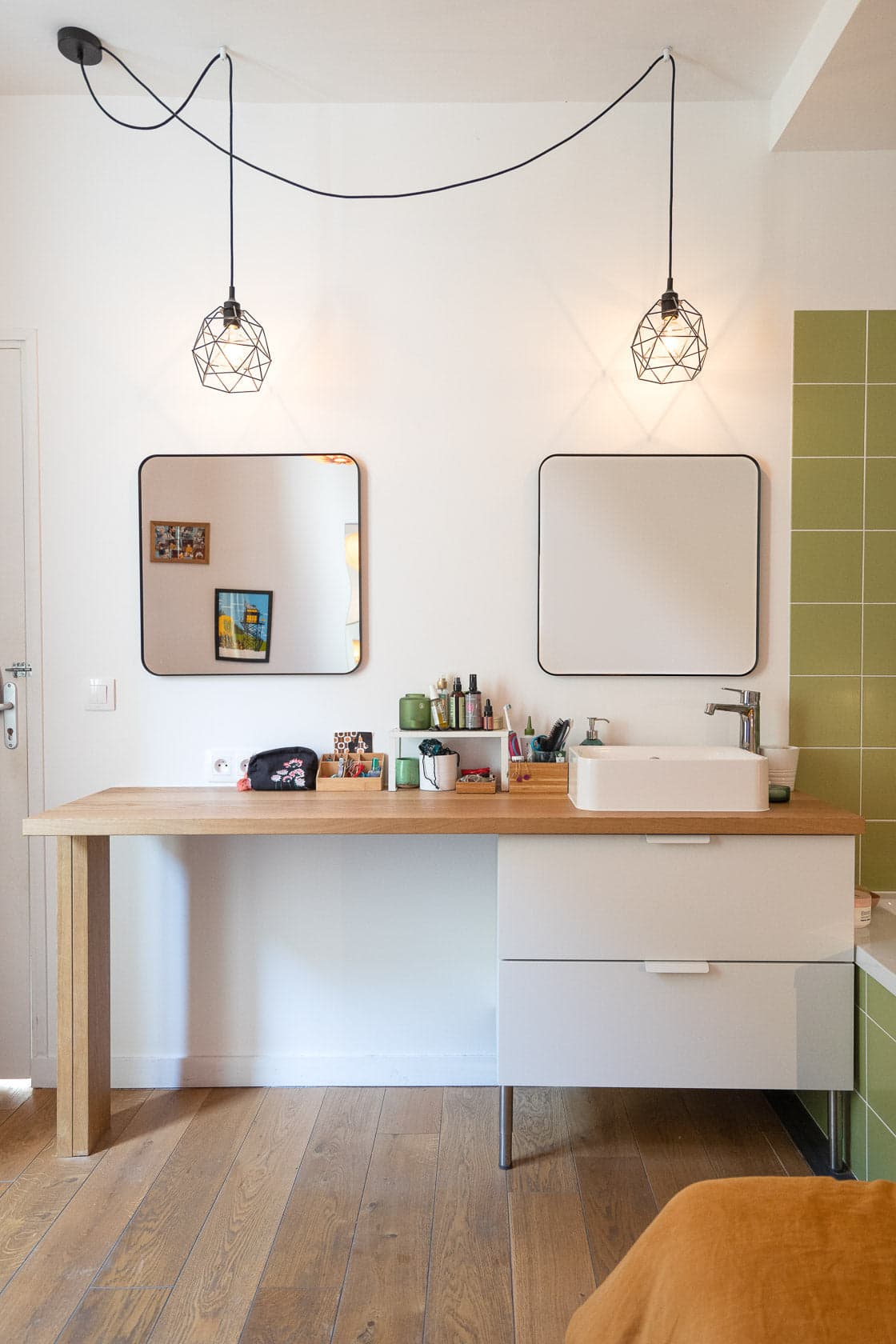 Chambre avec bureau bois, suspensions géométriques noires et pan de mur végétal