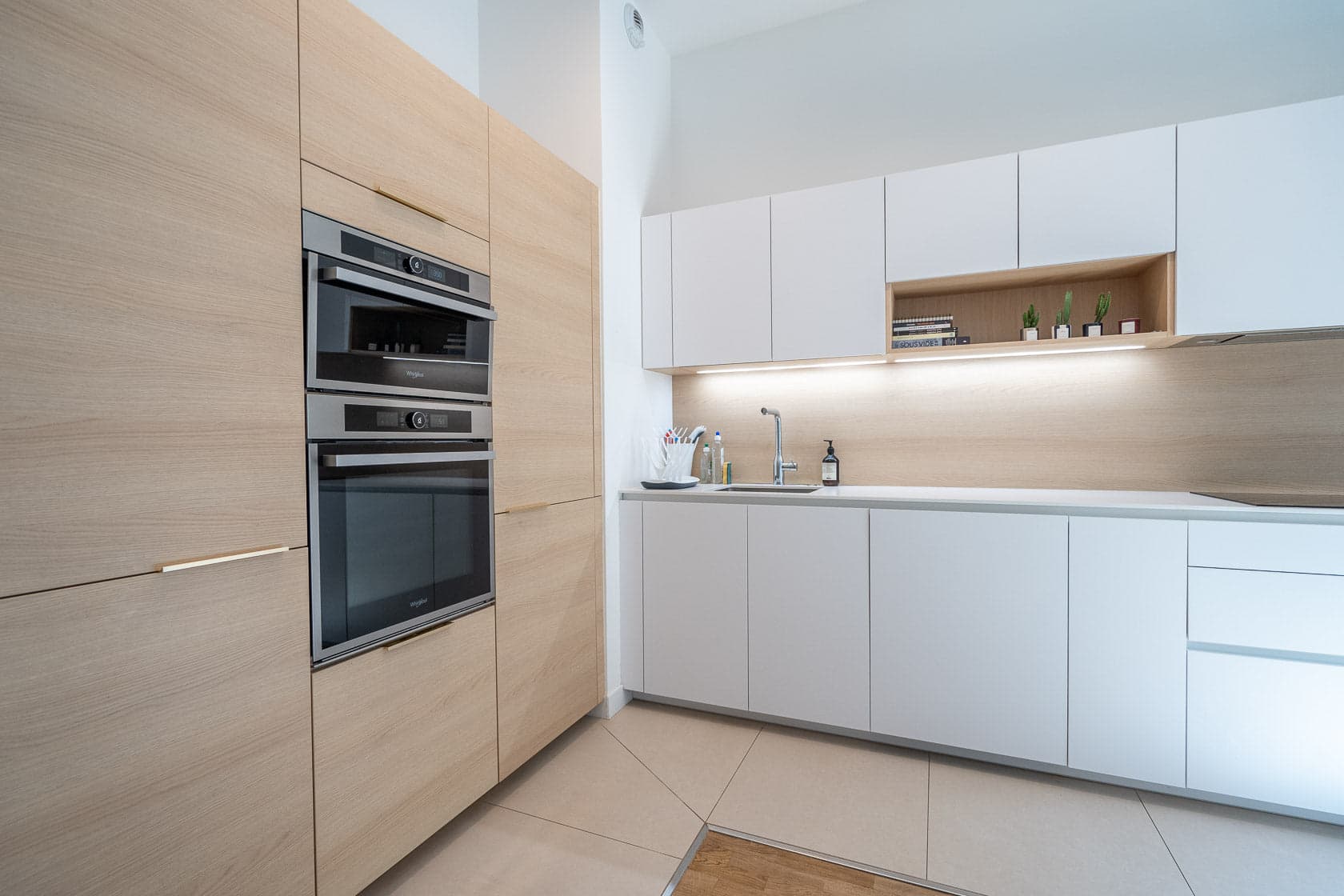 Cuisine moderne en bois clair, double four encastré et plan de travail blanc