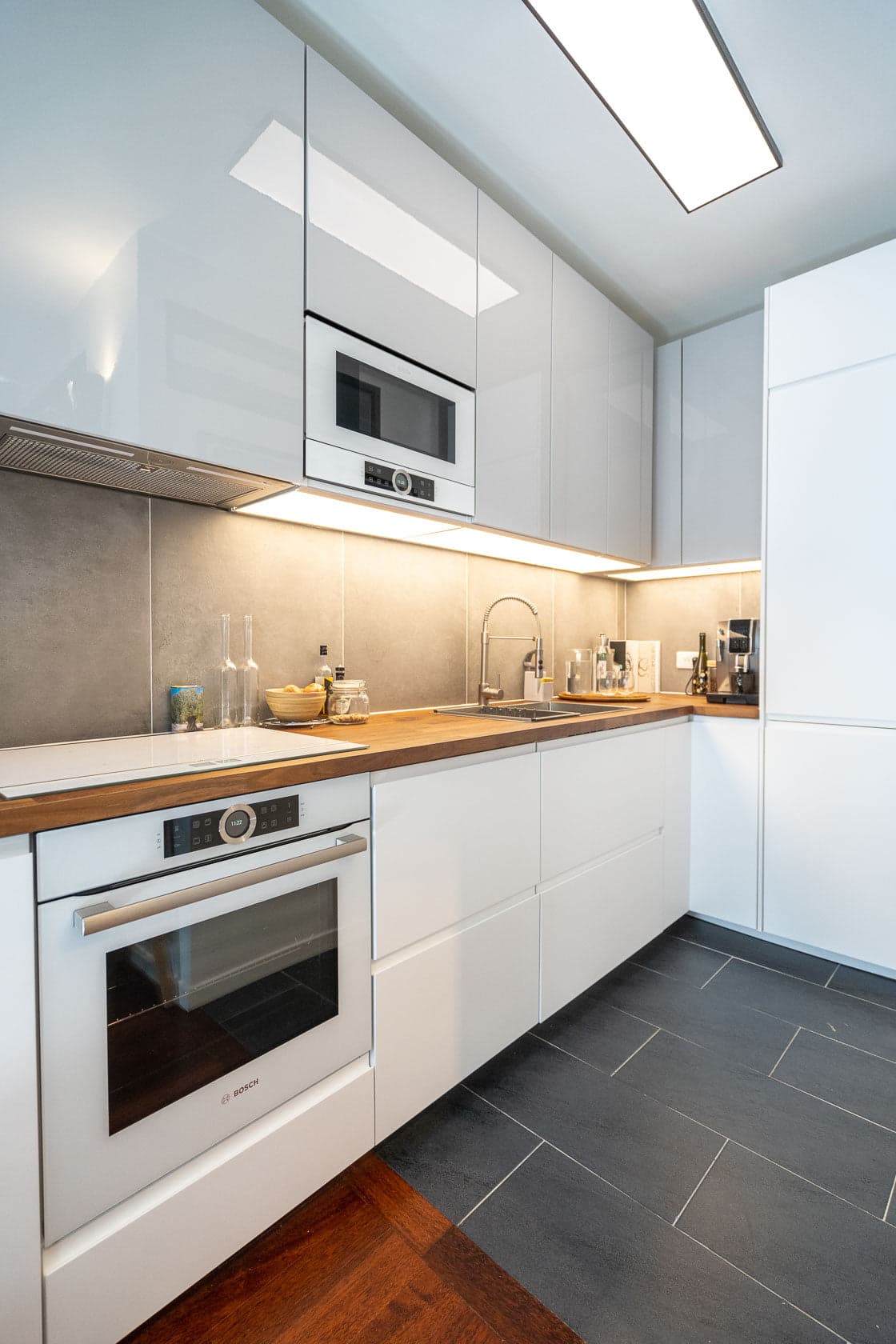 Cuisine blanche laquée en L, plan de travail bois et crédence effet béton