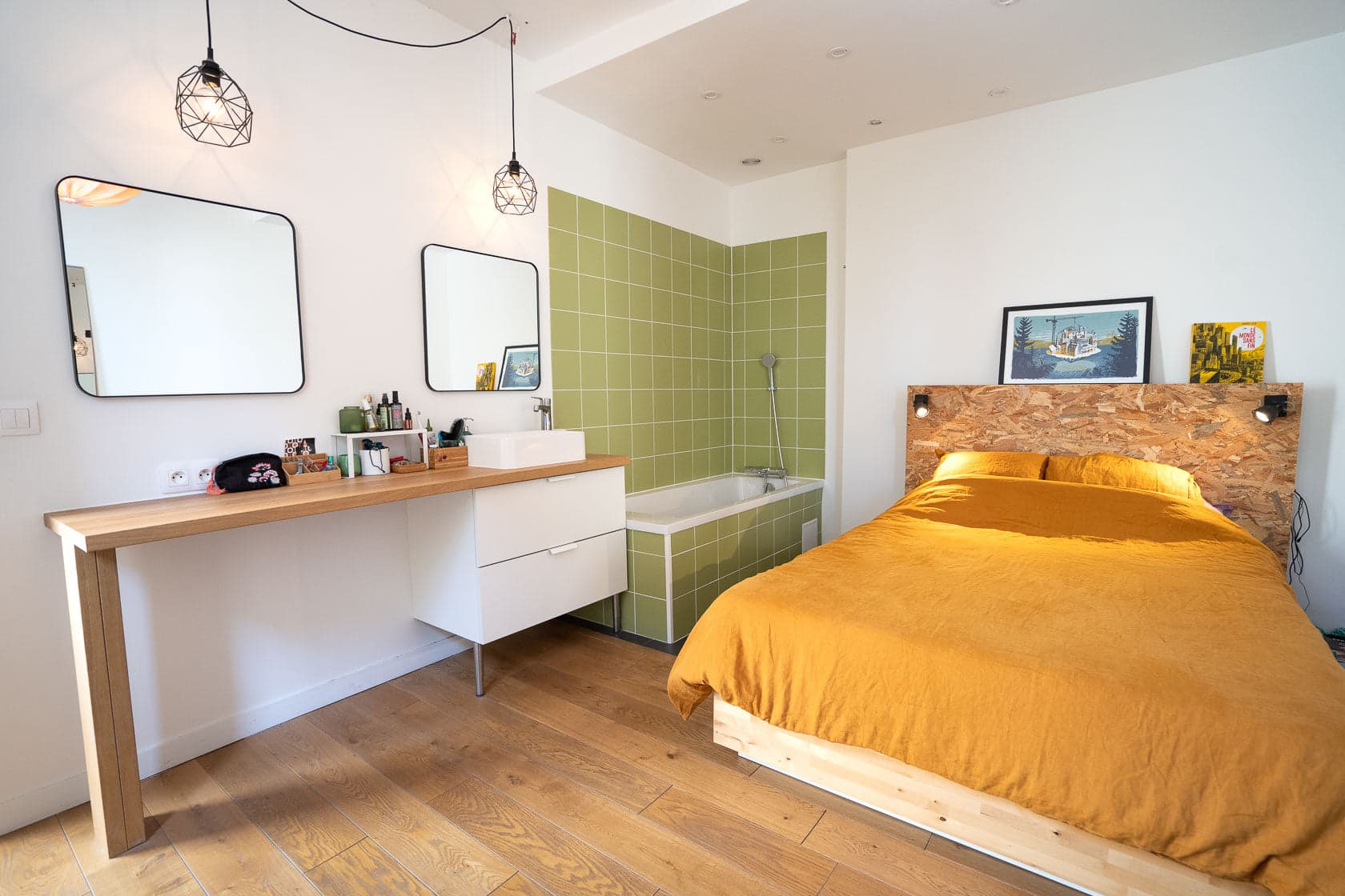 Chambre avec couette moutarde, tête de lit bois brut et salle de bain ouverte carrelage vert