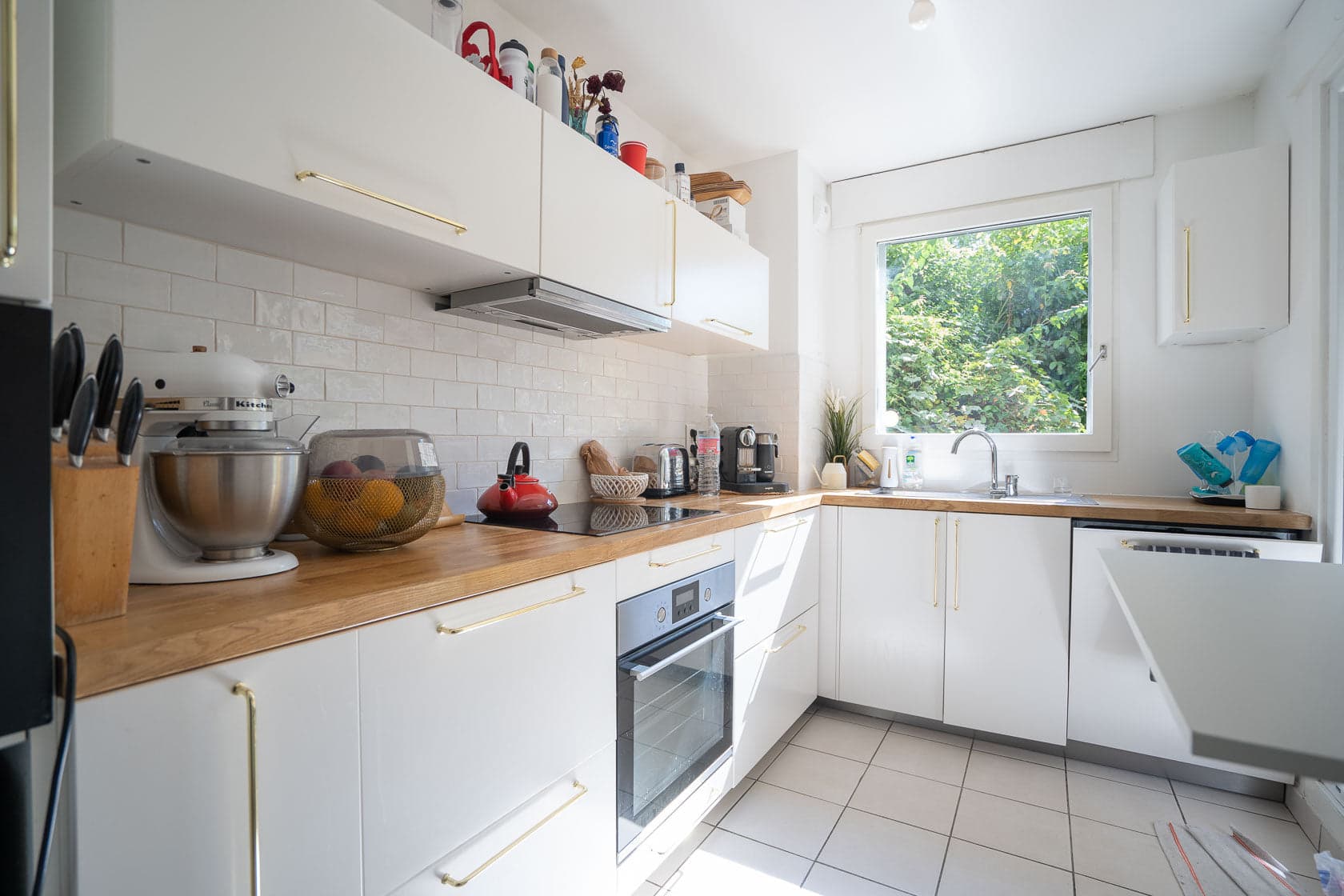 Cuisine blanche en L, poignées laiton et crédence carrelage blanc