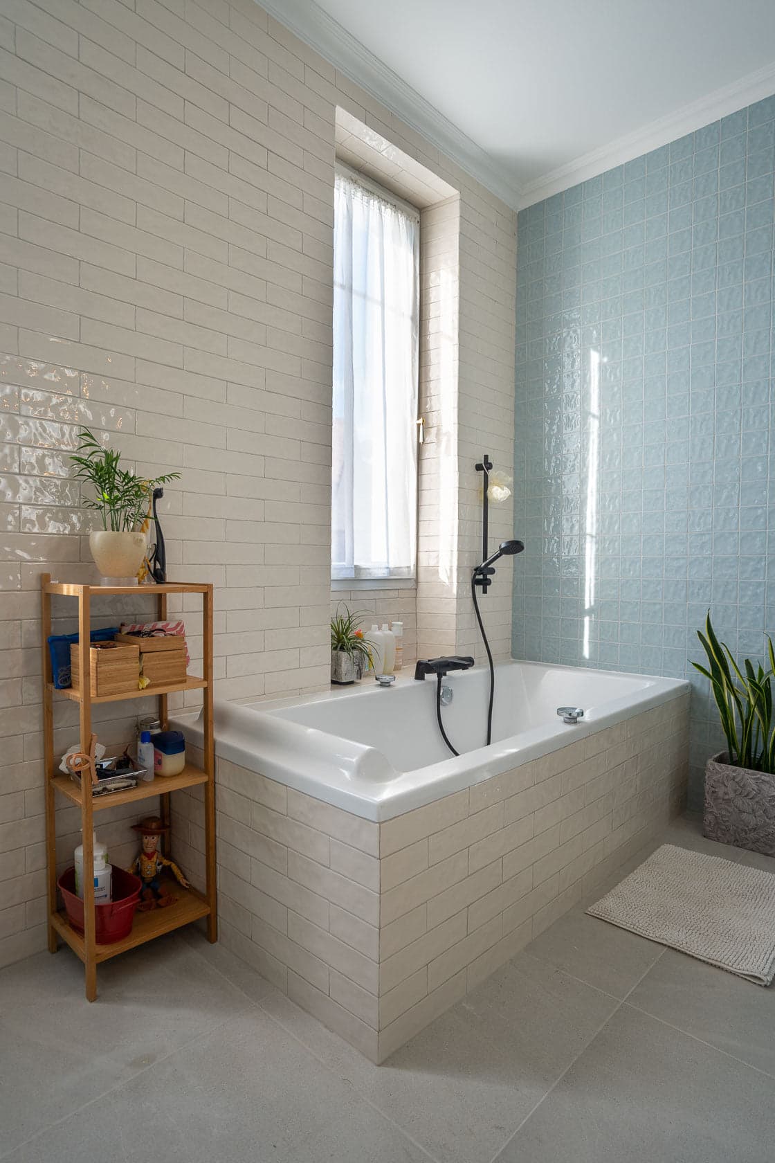 Salle de bain carrelage beige et bleu, baignoire et fenêtre lumineuse