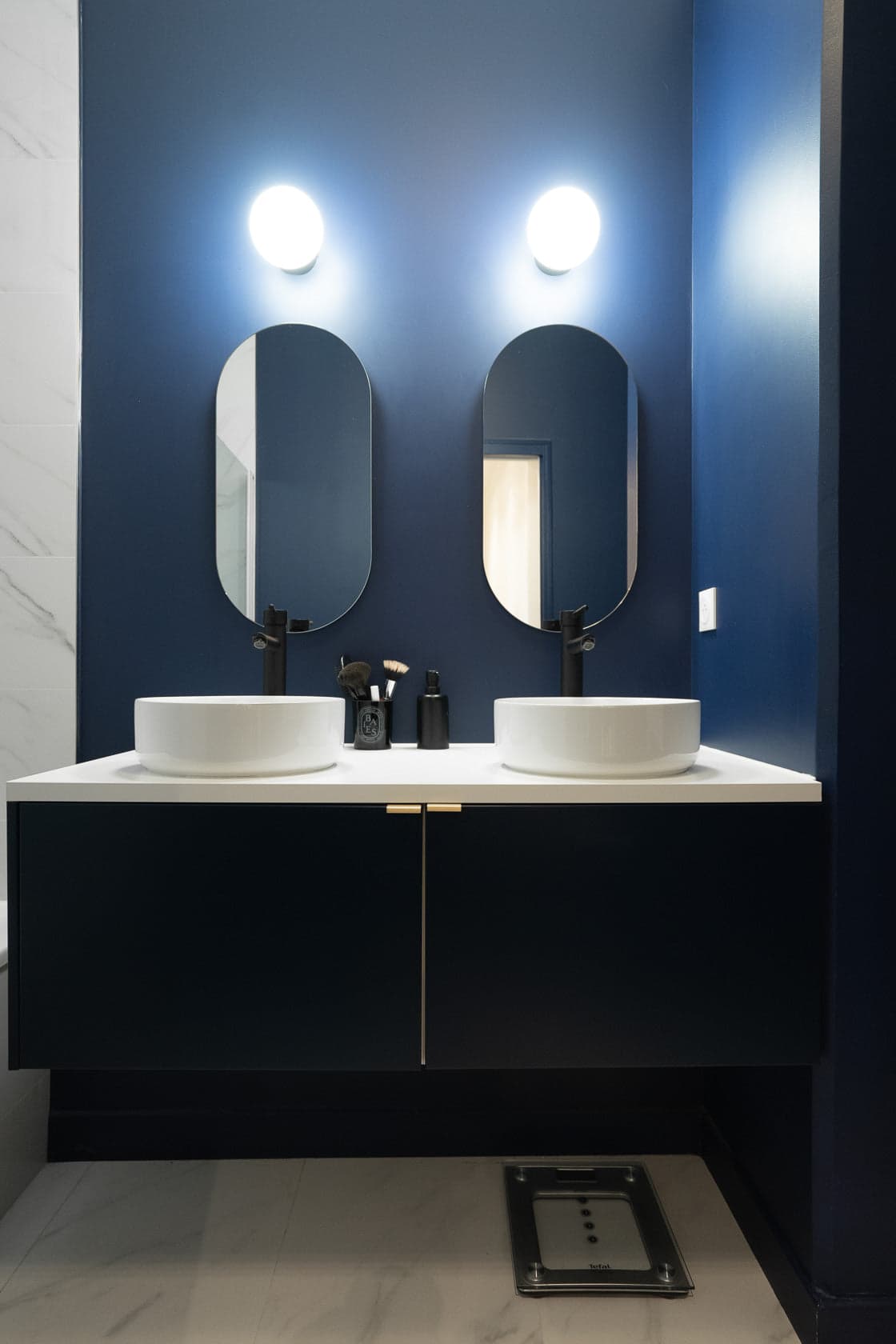 Salle de bain double vasque, murs bleu nuit et miroirs ovales rétroéclairés