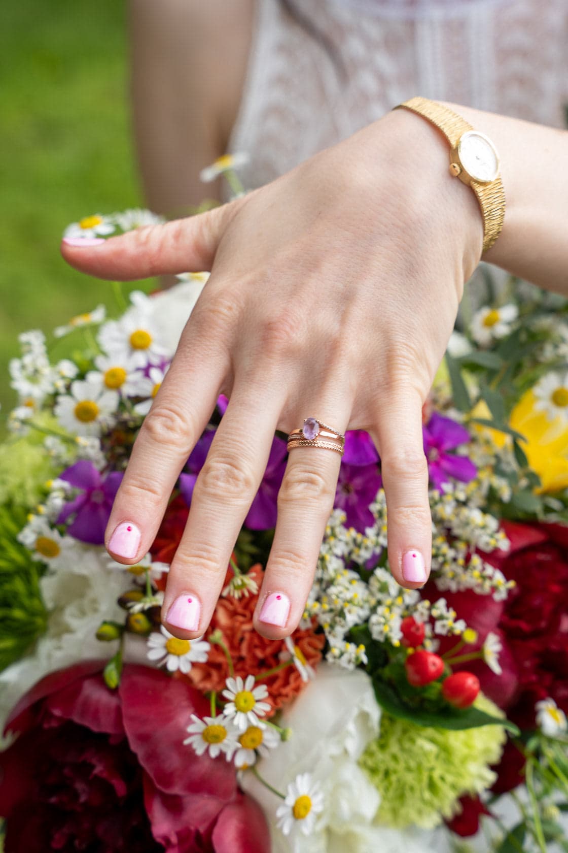 Mains de la mariée avec son alliance, posées sur un bouquet floral, symbolisant l'union et l'émotion du mariage.