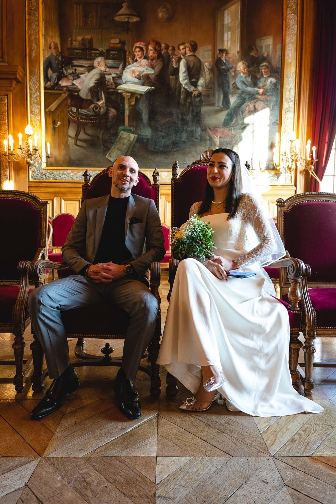 Couple de mariés assis dans la salle des mariages de la mairie du 19ème arrondissement de Paris.