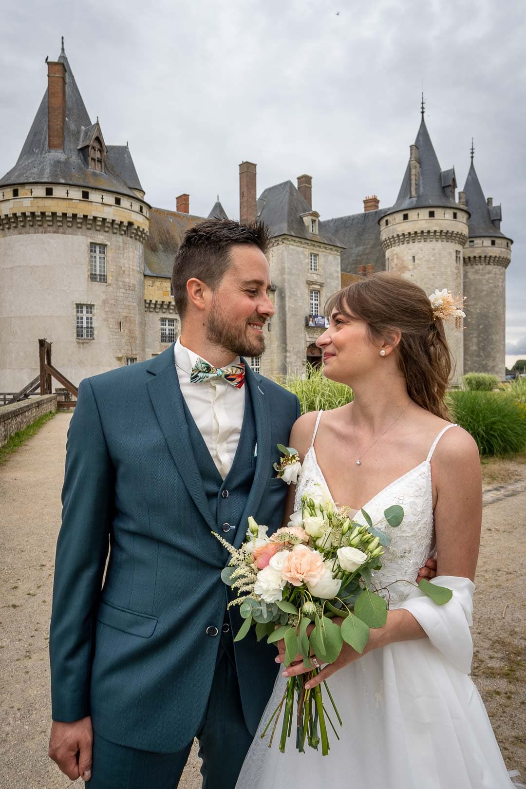 Les jeunes mariés posent avec élégance devant le château de Sully
