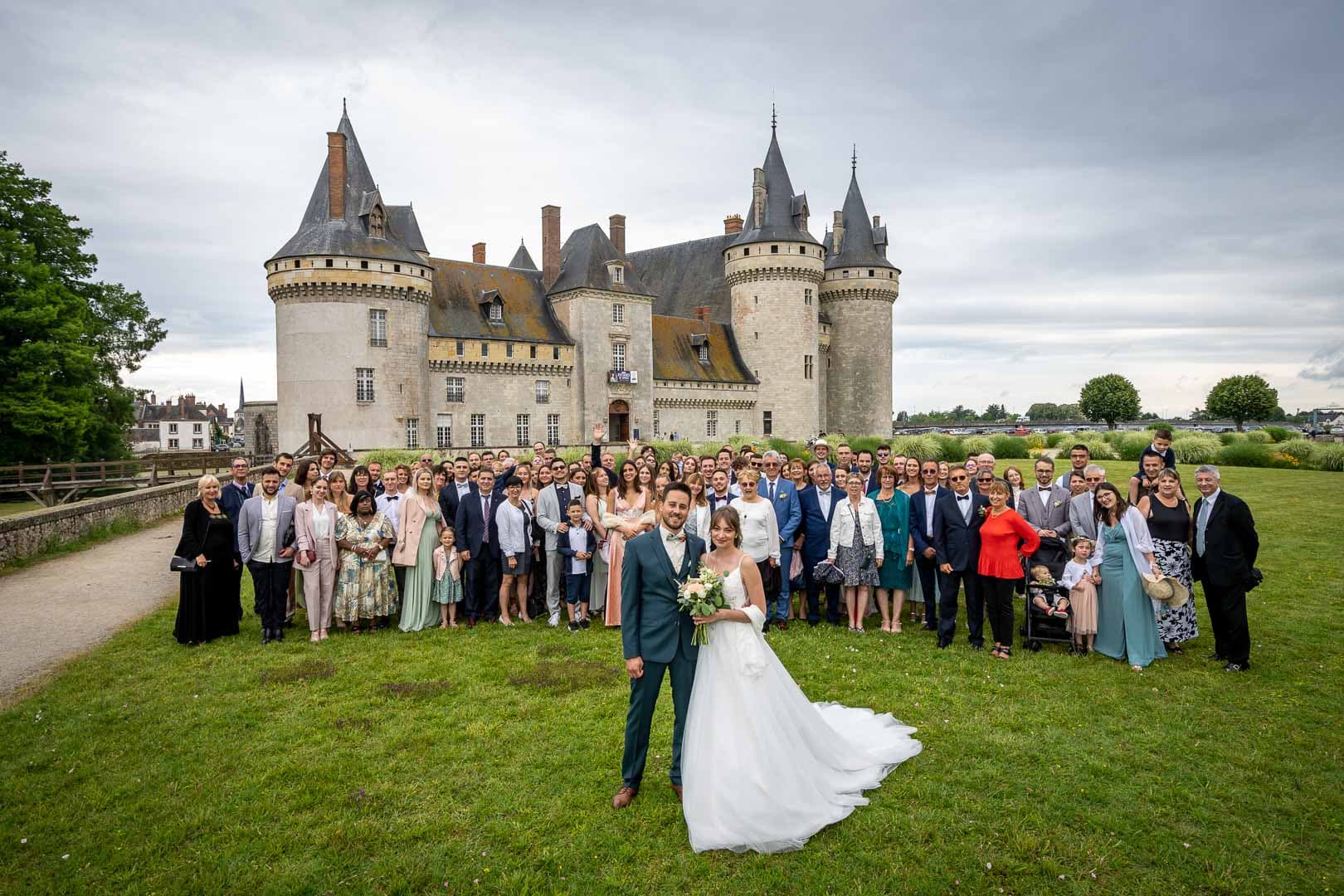 Les mariés entourés de leurs invités pour une photo de groupe devant le château de Sully