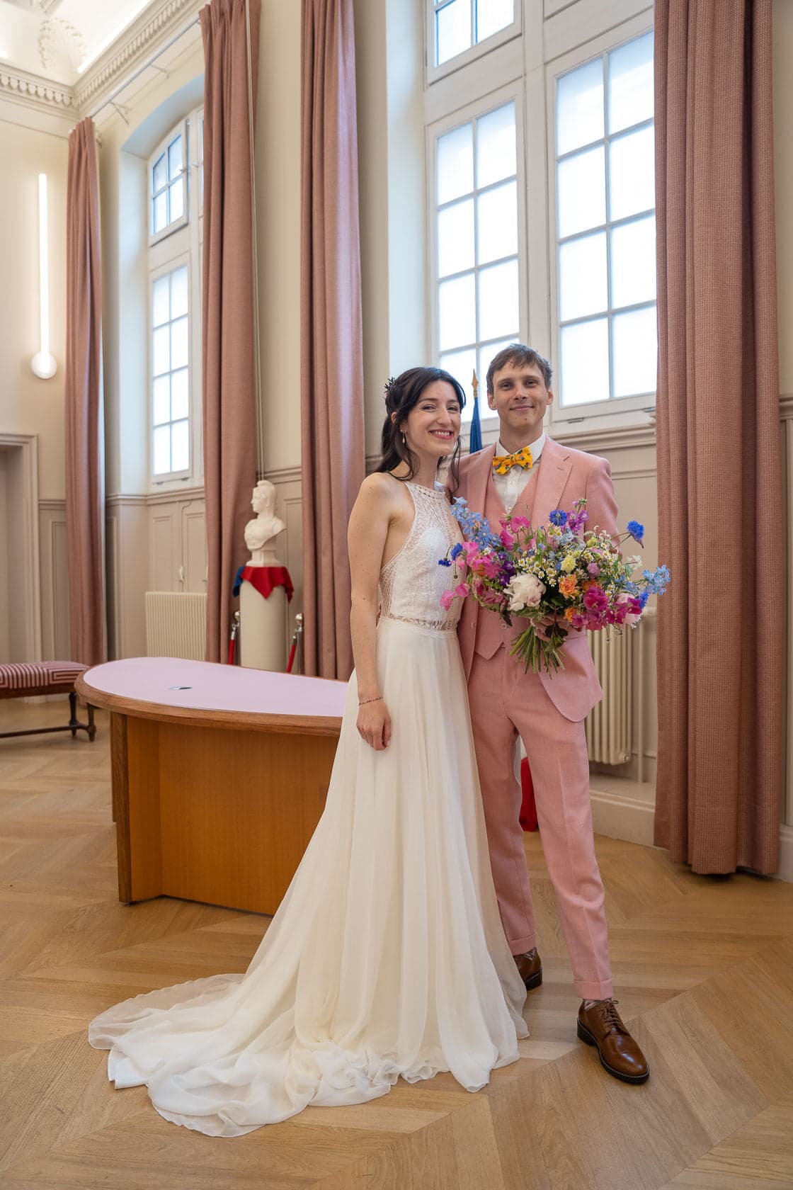 Les mariés à la mairie après la cérémonie civile, arborant des tenues élégantes avec un bouquet coloré, symbolisant leur bonheur.