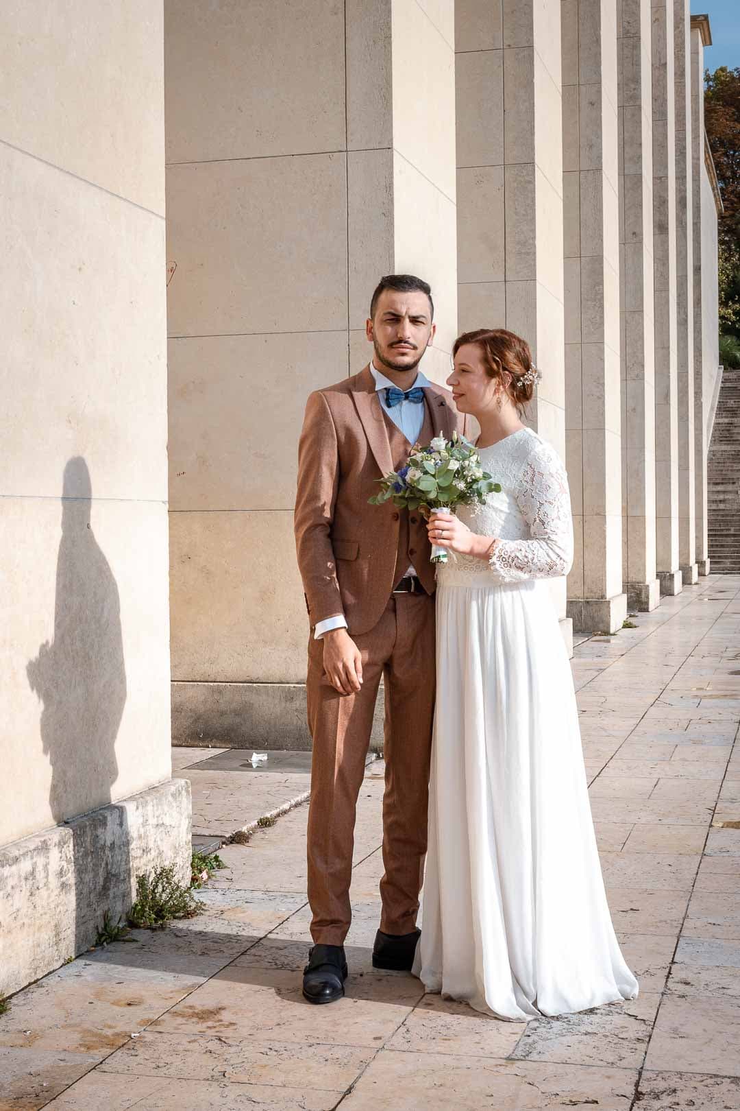 Couple de mariés posant devant les emblématiques piliers du Trocadéro.
