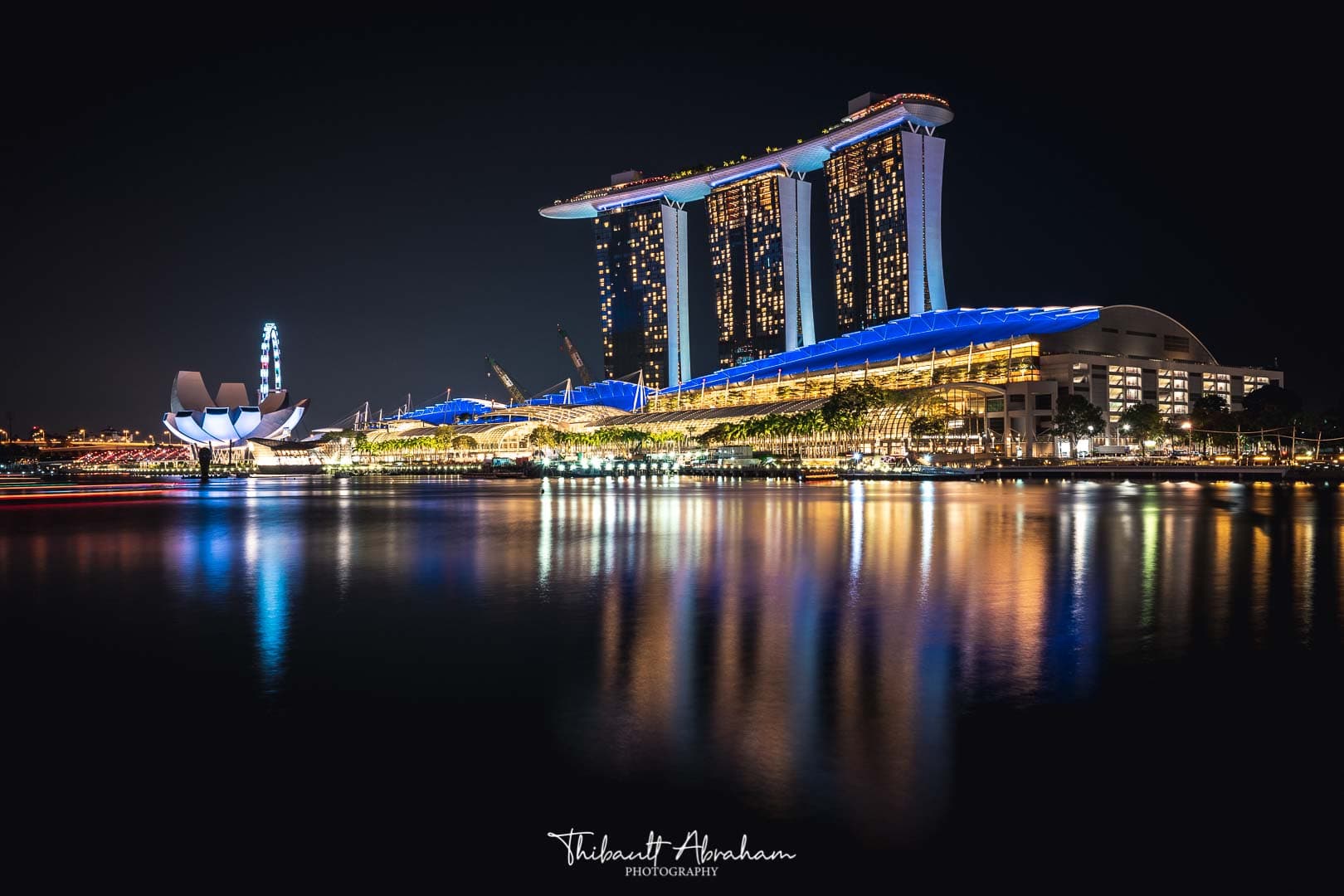 L'hôtel de luxe Marina Bay Sands illumine et se reflette à la surface de l'eau pendant la nuit à Singapour
