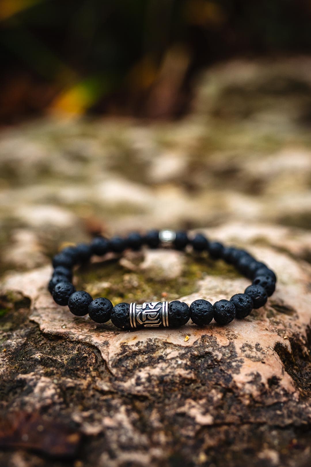 Photographie professionnelle de packshot produit pour bracelet noir et argent en pierre de lave sur roche