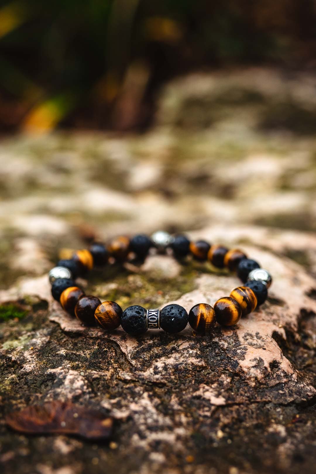 Photographie professionnelle de packshot produit pour bracelet coloré en pierre de lave et œil de tigre sur roche