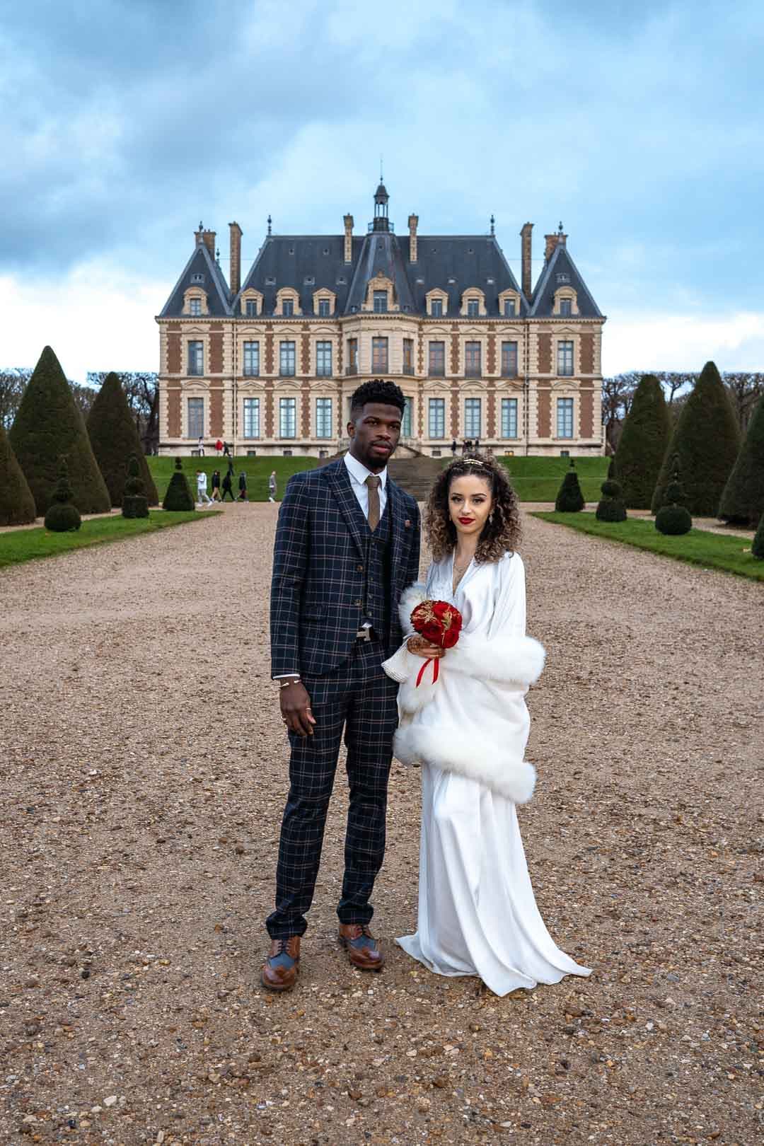 Jeunes mariés posant fièrement devant le château du Parc de Sceau.