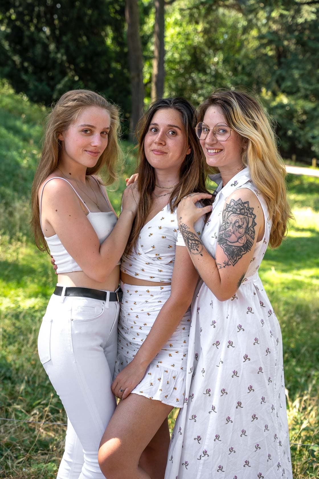 Trois jeunes femmes souriantes posant ensemble dans un parc ensoleillé à Paris