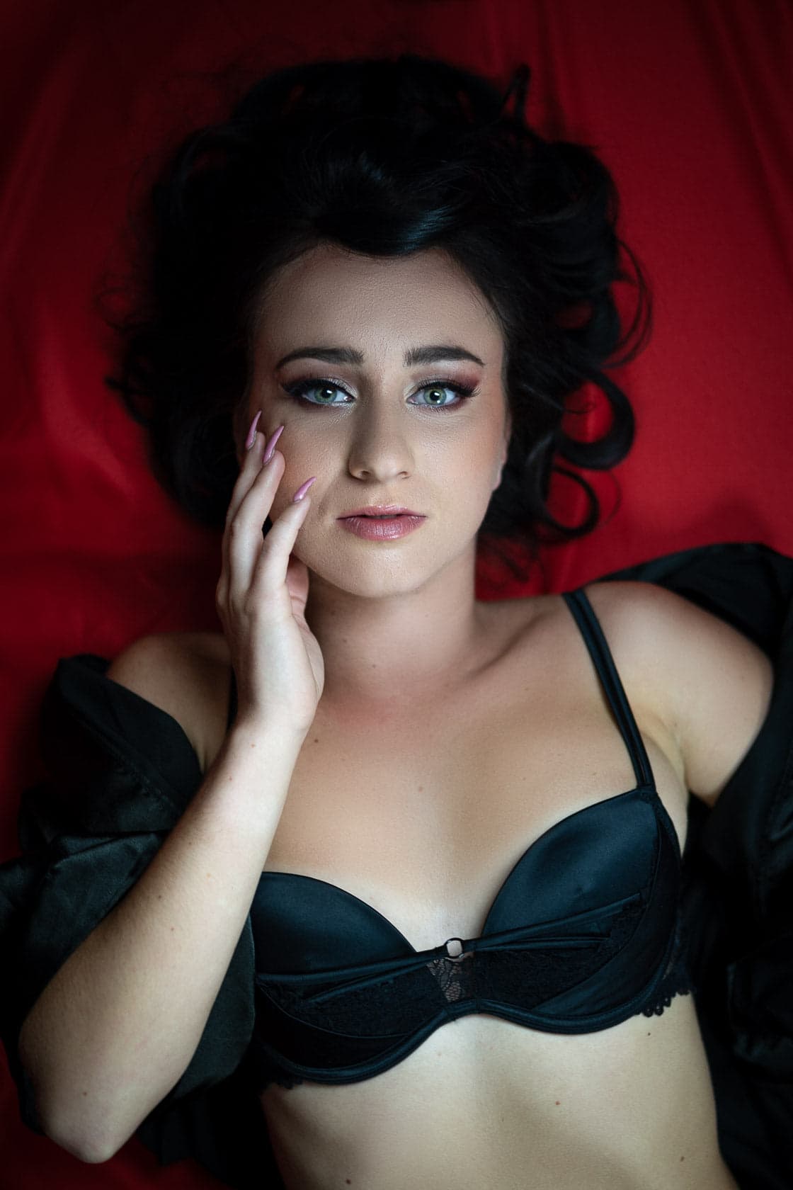 Portrait de femme en soutien-gorge noir sur fond rouge en studio