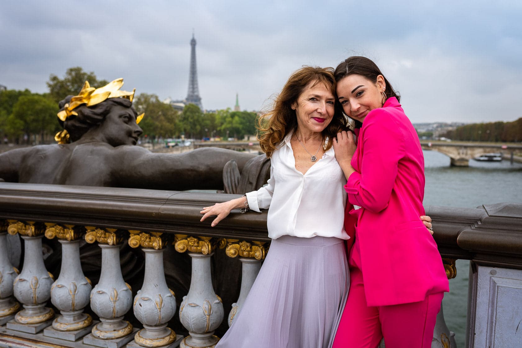 Mère et fille souriantes posant sur le Pont Alexandre III à Paris avec la Tour Eiffel en arrière-plan