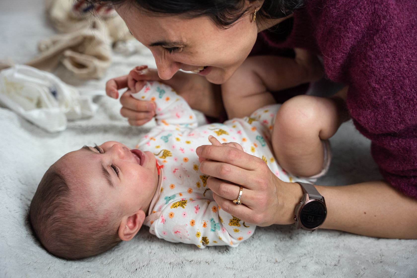 Mère souriante interagissant avec son bébé allongé sur une couverture