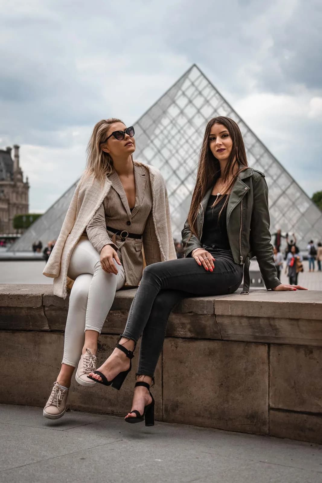 Deux amies assises devant la pyramide du Louvre
