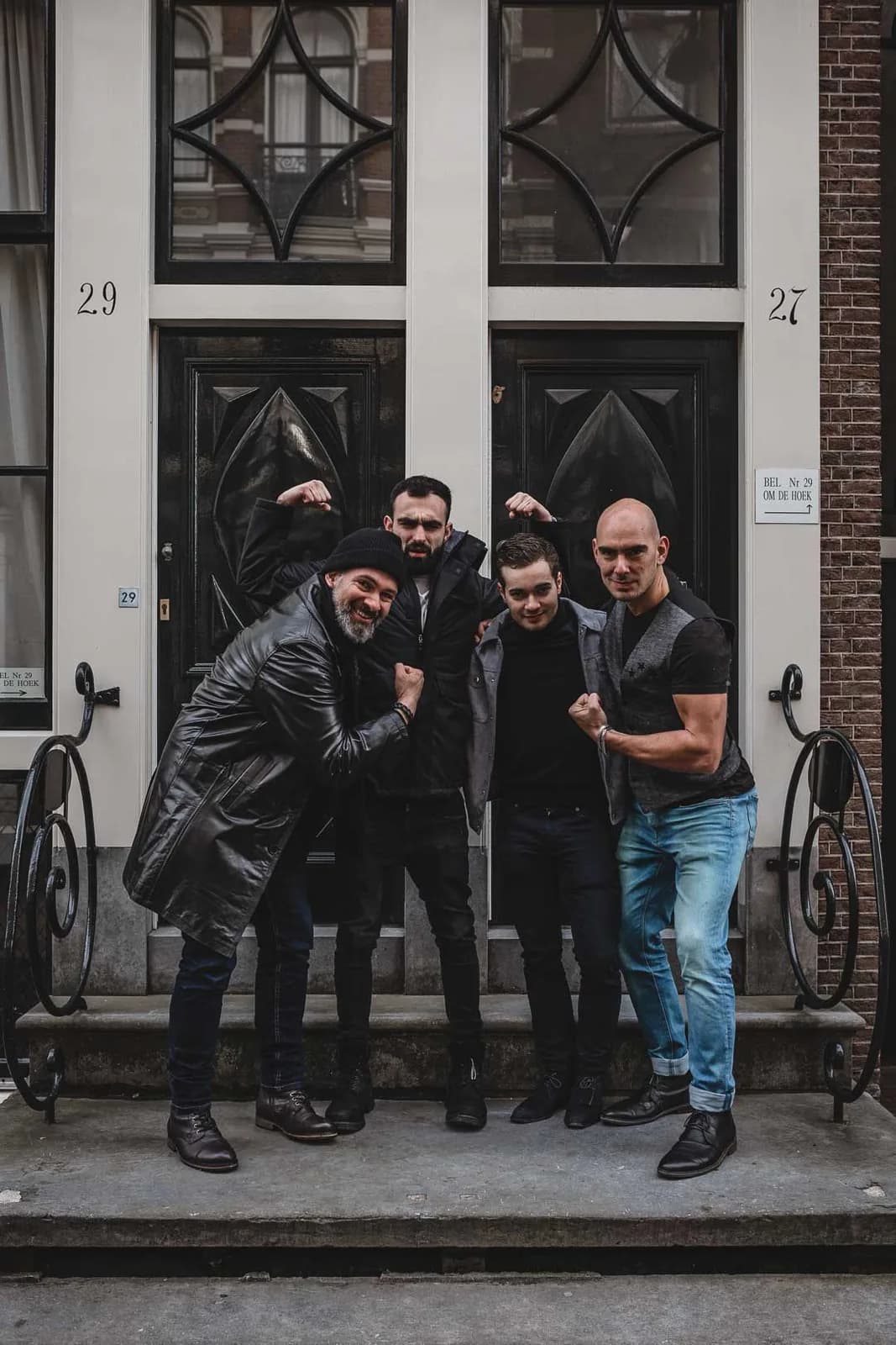 Quatre amis posant biceps bandés devant une porte noire