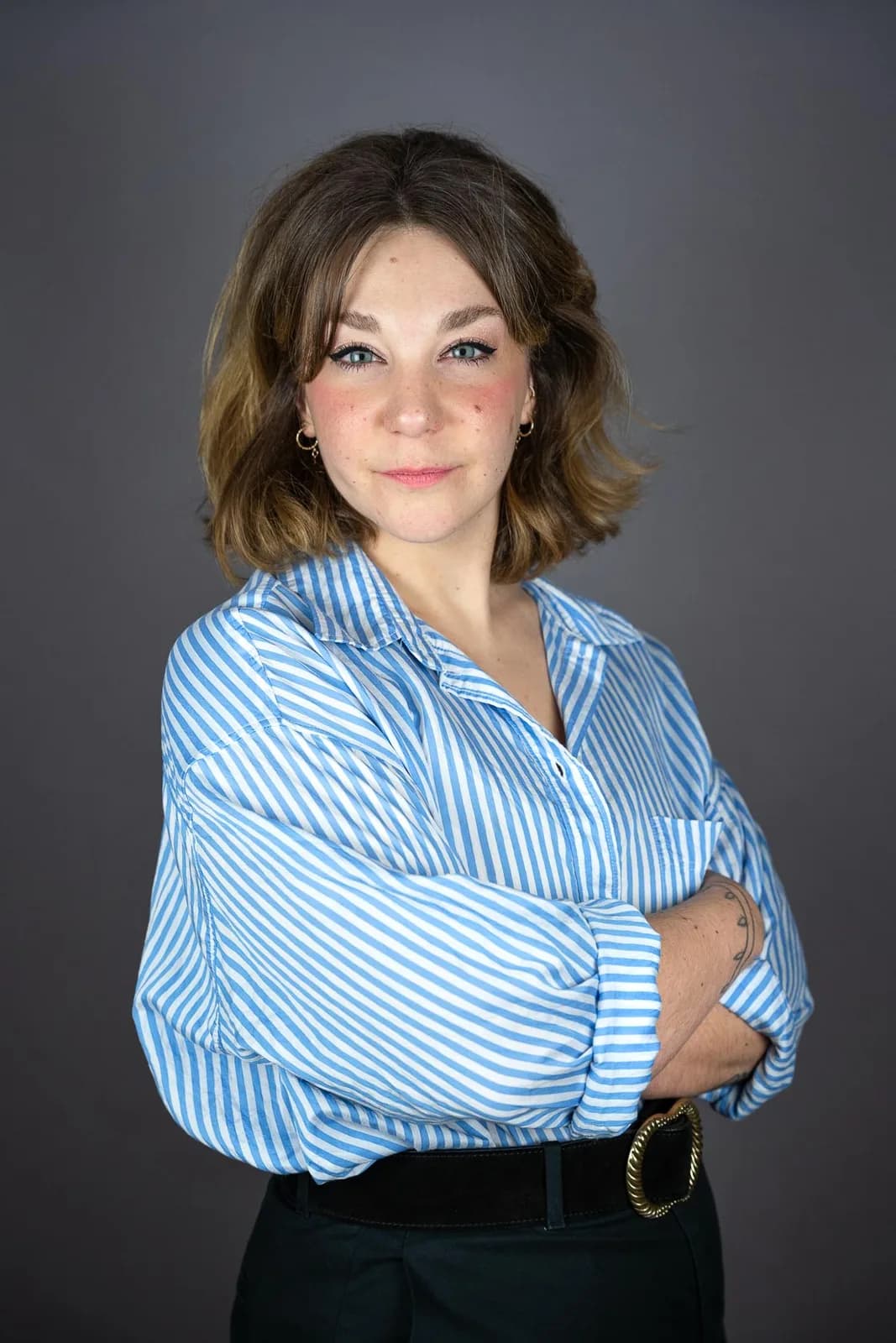 Femme en chemise rayée bleue, bras croisés