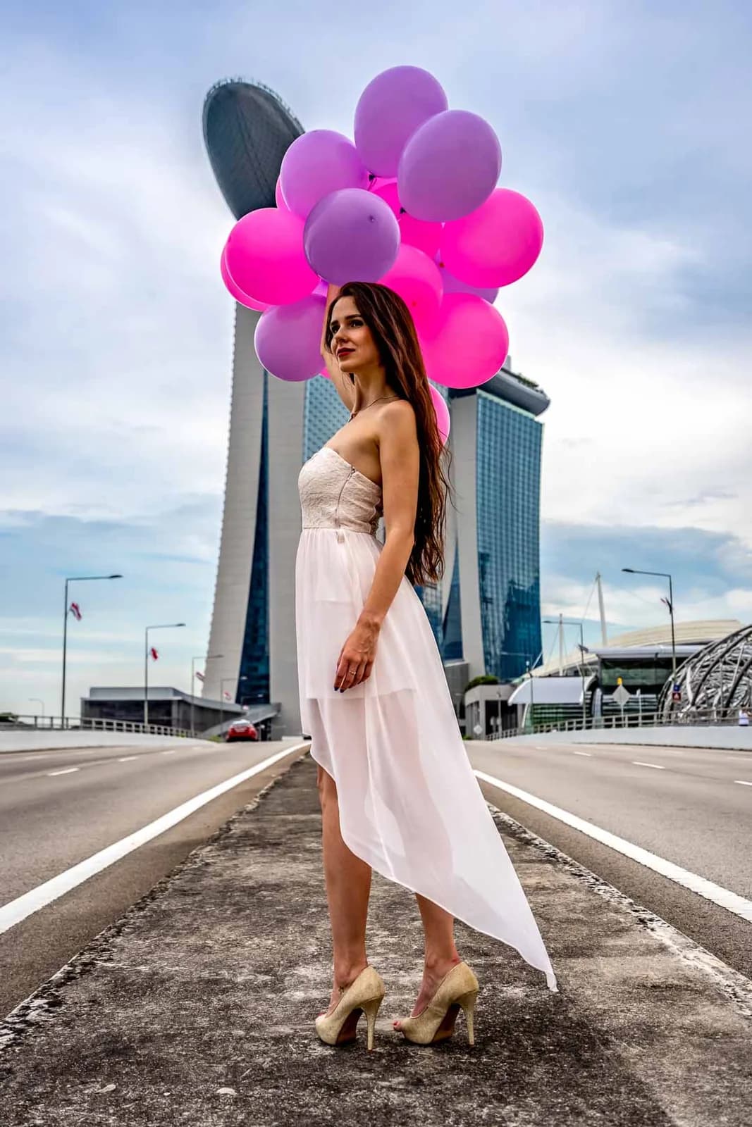 Femme en robe blanche avec ballons devant Marina Bay