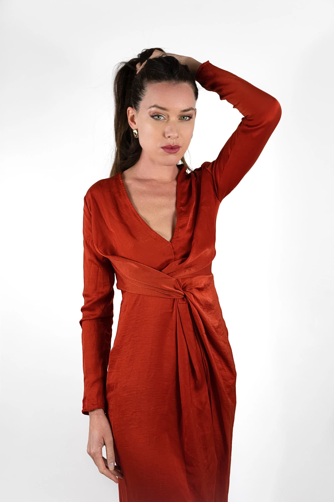 Mannequin en robe satinée rouille, main dans les cheveux, portrait studio fond blanc