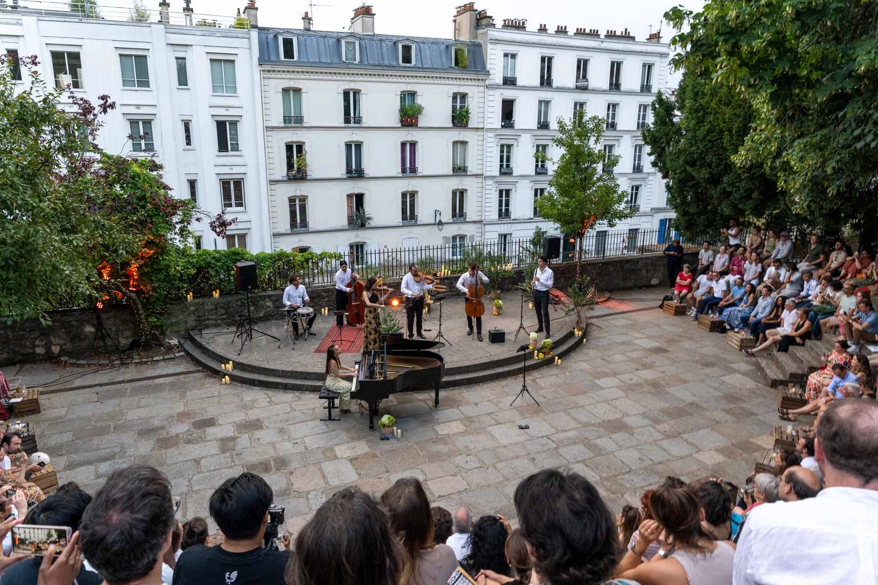 Ensemble de musiciens au crépuscule, devant les façades parisiennes, Arènes musicales de Montmartre