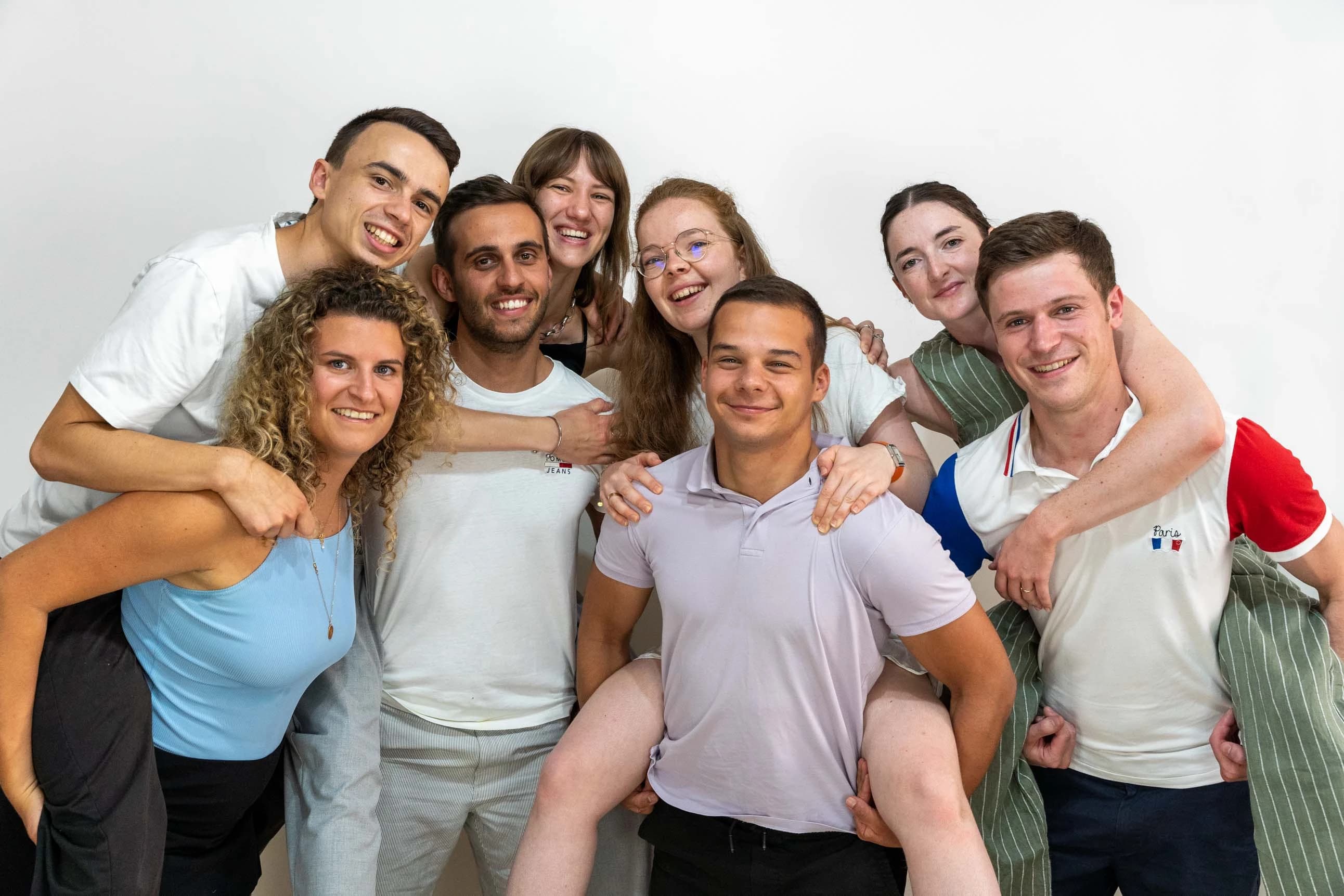 Group of friends indoors, poses close together in a cascade