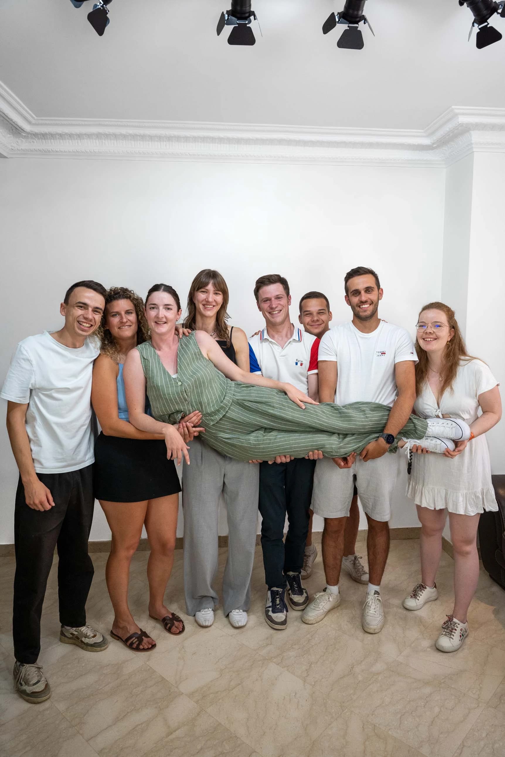Group of friends indoors, a friend being carried laughing