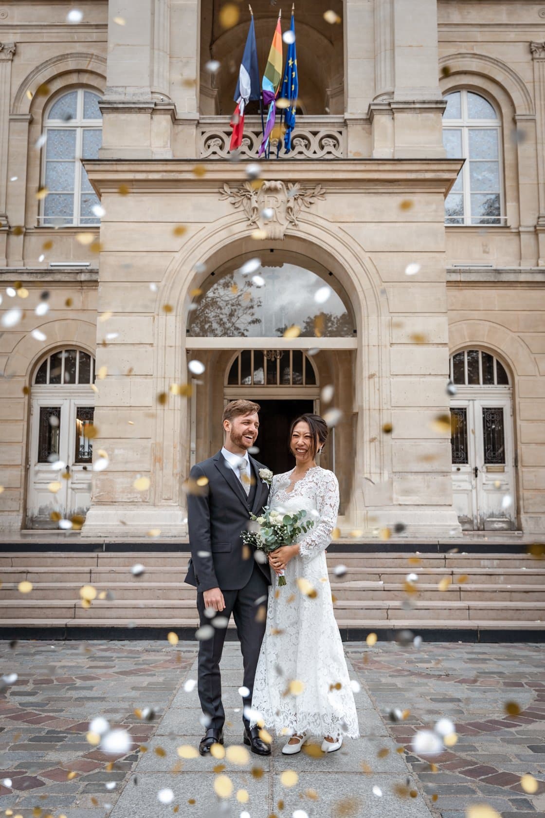 Joie des mariés sous une pluie de confettis or et argent à la sortie de la mairie