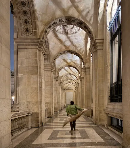 Homme en mouvement dans une galerie voûtée en pierre du musée du Louvre