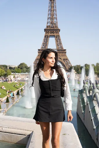 Femme en robe noire et chemisier blanc face à la tour Eiffel, fontaines du Trocadéro en arrière-plan