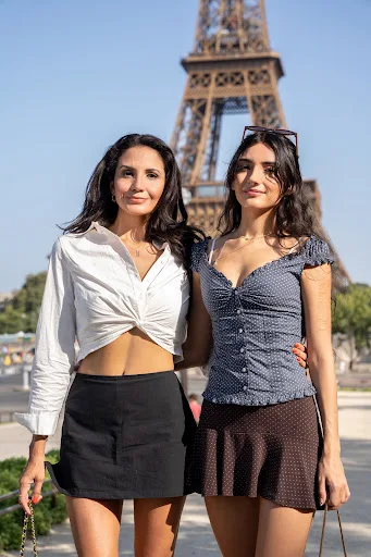 Deux femmes souriantes posant bras dessus bras dessous devant la tour Eiffel